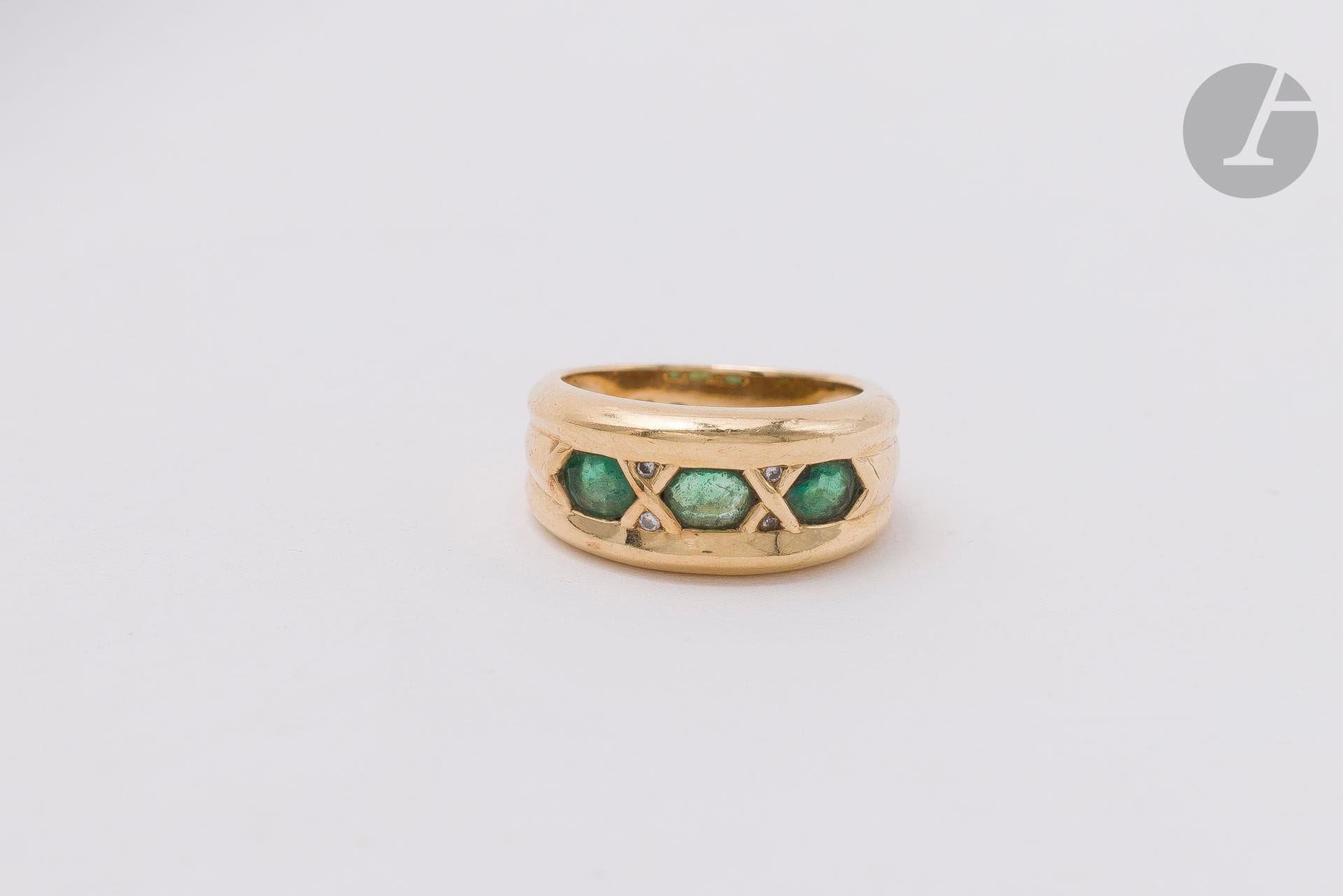 Bague en or 18K (750) sertie de 3 émeraudes facettées ovales scandées de petits diamants de taille brillant. Travail français. Tour de doigt : 52. Poids brut : 7,4 g (égrisures, chocs, rayures)