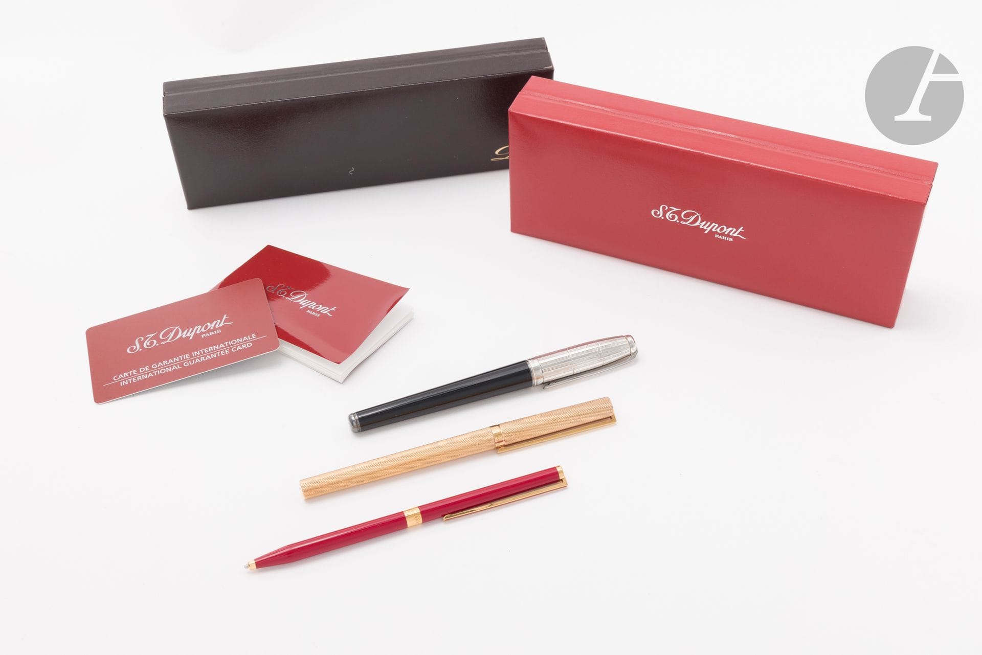 S.T. DUPONT
Suite de trois stylos comprenant : un stylo plume en métal doré guilloché, la plume en or 18K (750) ; un porte mine en laque de chine rouge, les extrémités en métal doré ;  et un stylo bille laqué noir, le capuchon en métal argenté à décor de stries. Les trois signés et numérotés. Le premier conservé dans son écrin et le second conservé dans son écrin et sa sur-boîte (en l'état)