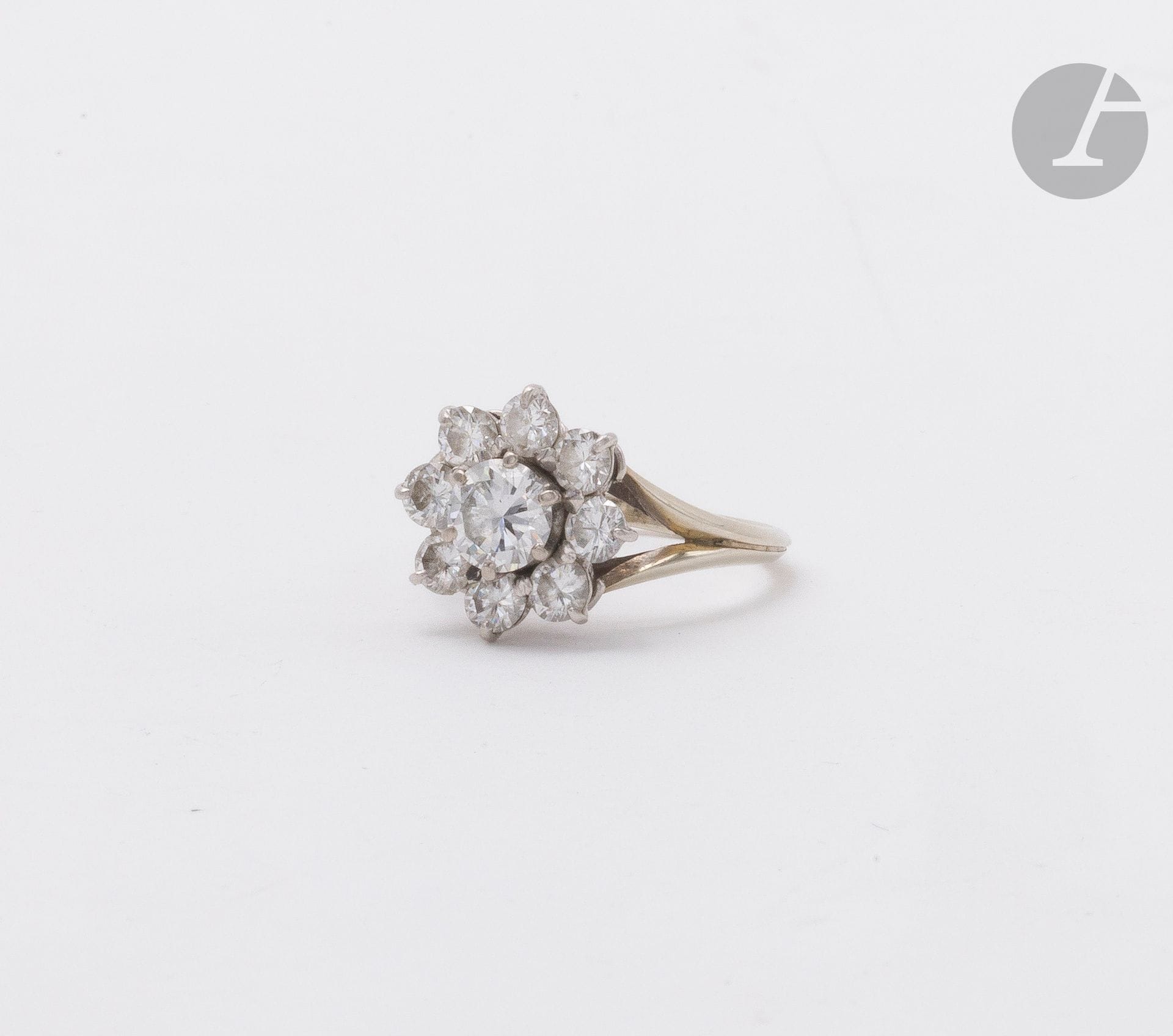 Bague fleur en or gris 18K (750) et platine, le cœur serti d'un diamant rond de taille brillant dans un entourage de 8 diamants plus petits. Tour de doigt : 52. Poids brut : 3,9 g (égrisures)