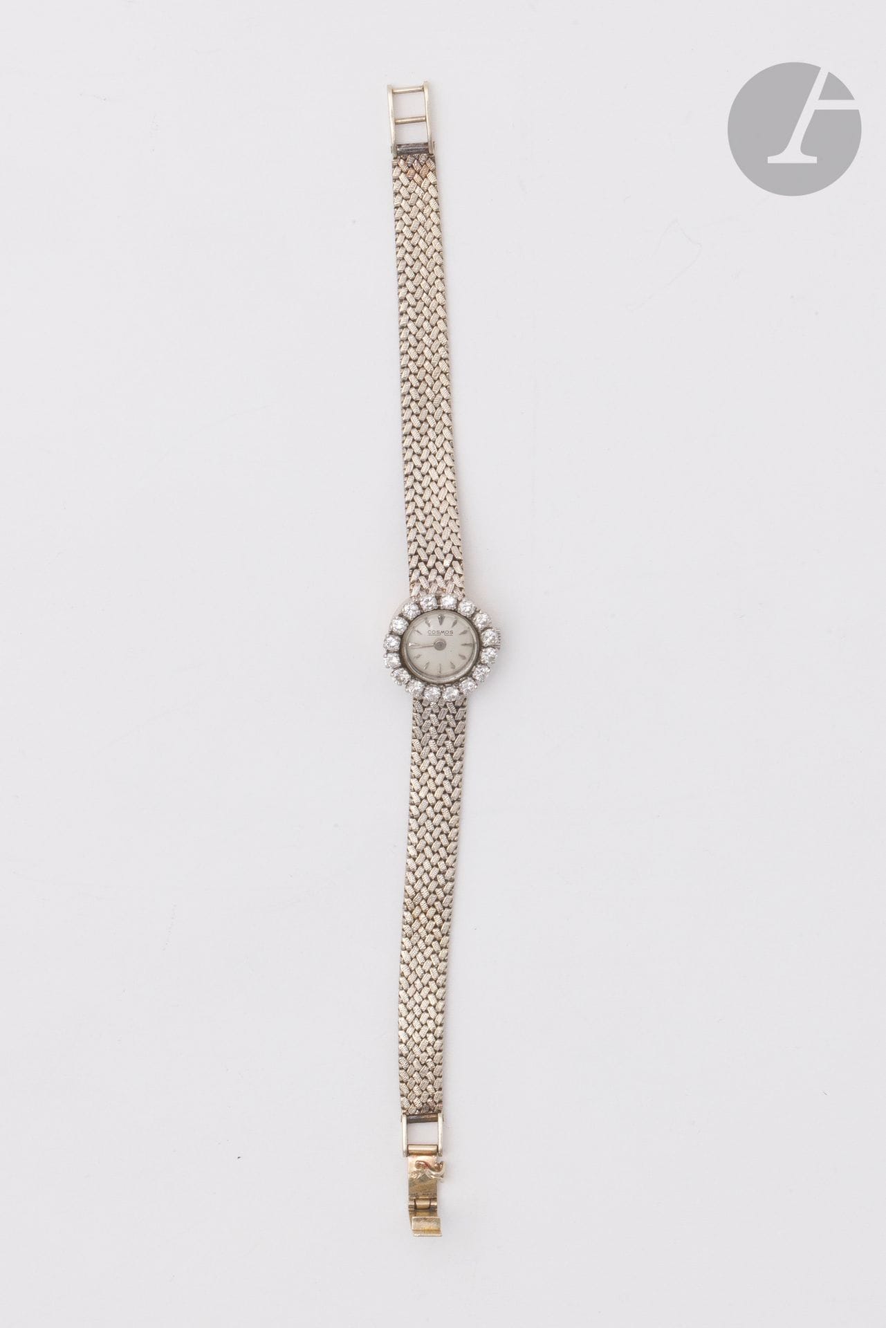 COSMOS
Montre de dame en or gris 18K (750), cadran rond serti de 16 diamants ronds de taille brillant, index bâtons, mouvement mécanique, bracelet souple en ruban d'or gris 18K. Travail français. Cadran signé. Longueur : 16 cm environ. Poids brut : 25,8 g (fonctionnement non garanti)