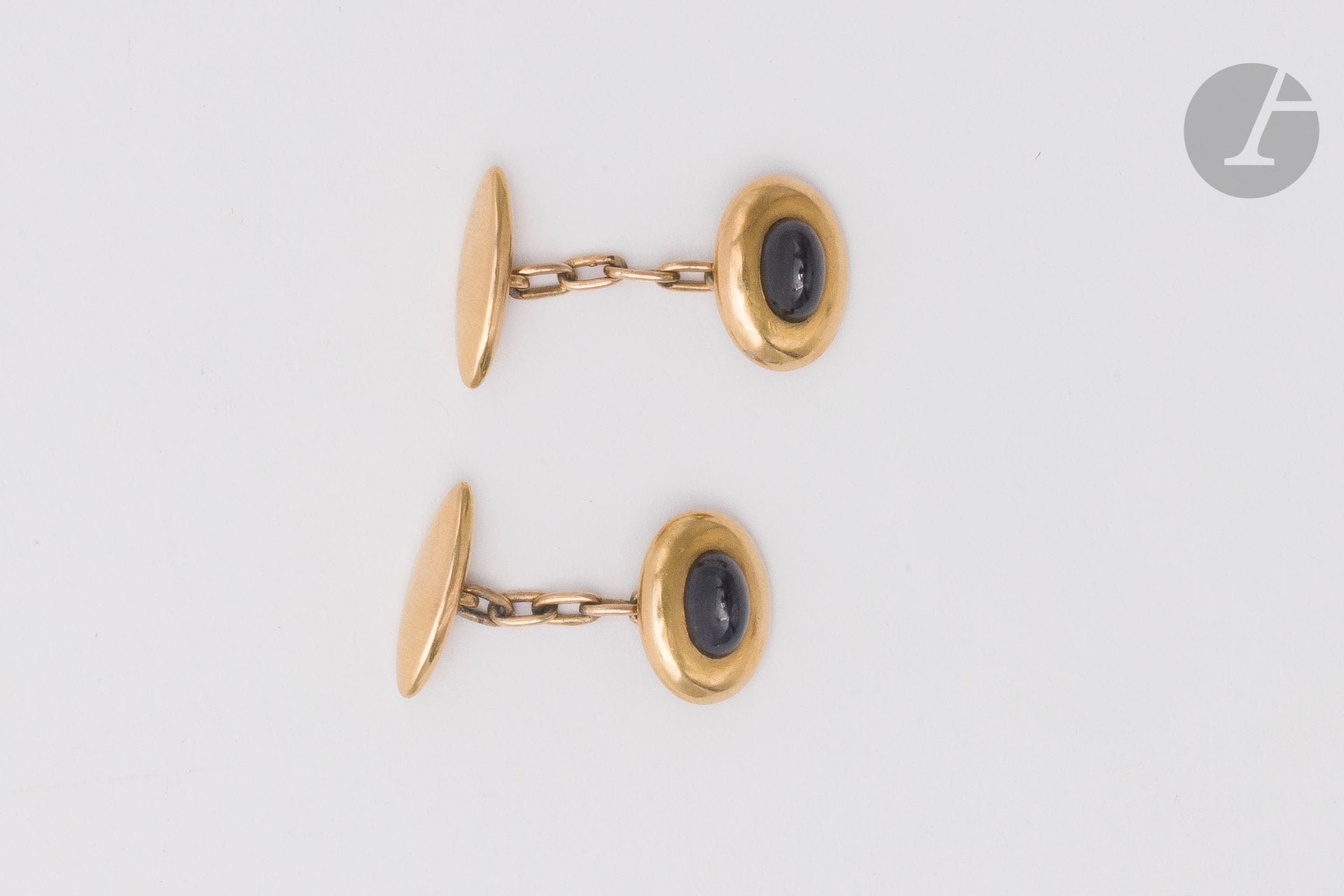 Paire de boutons de manchettes ovales en or 18K (750), chacun orné d'une pierre bleue cabochon. Dimensions : 1,7 x 1,2 cm environ. Poids brut : 7,9 g (égrisures, fêle interne)
