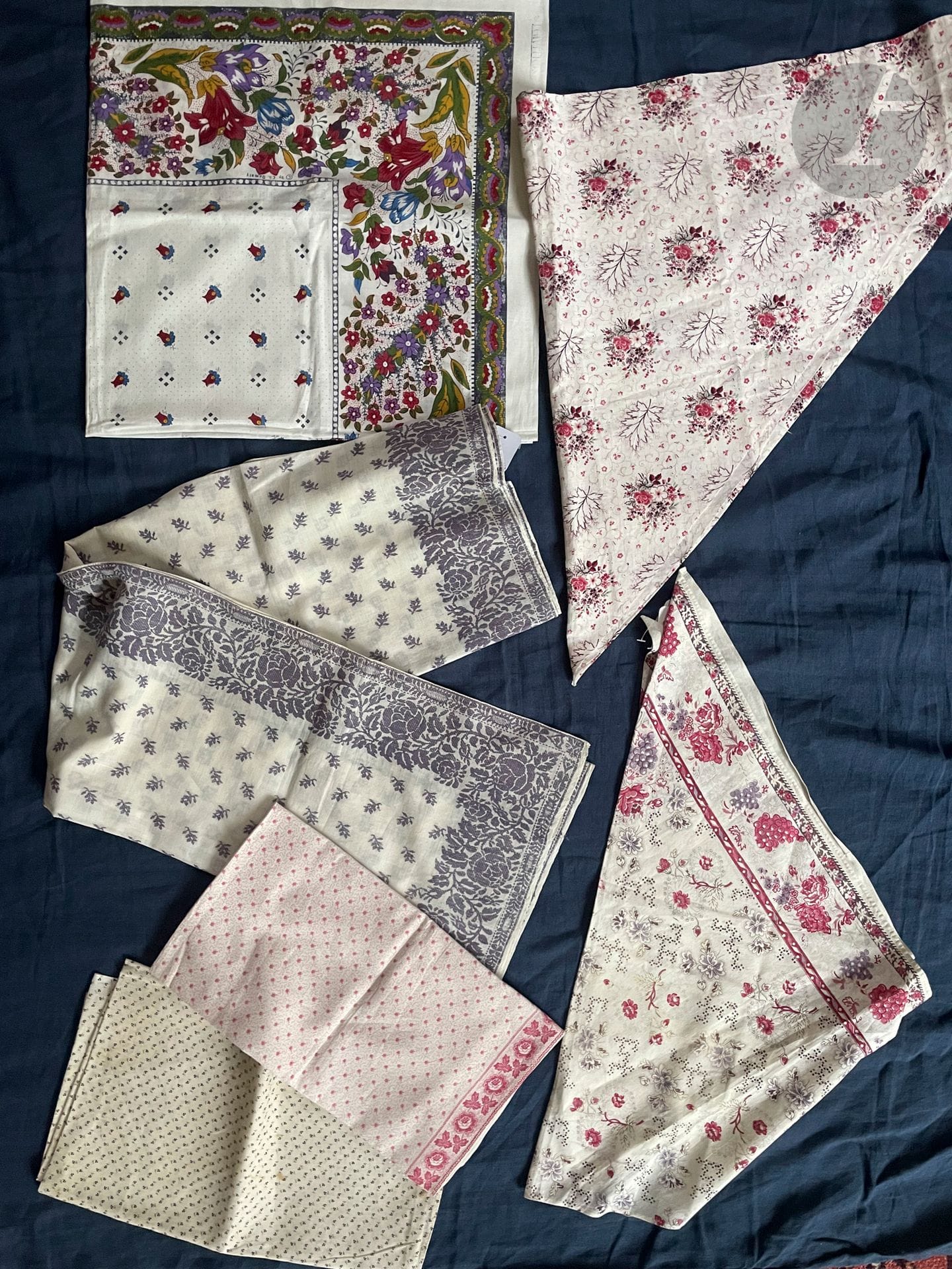 Set of 6 shawls, fichus and neckerchiefs in shaped and printed cotton with floral motifs, Alsace or Provence, late 19th and 20th century. Large purple wool brocaded cotton fichu with paisley decoration; 2 neck handkerchiefs in Augusta or mignonette monochrome and 2 fichus with triangular cut-out printed with roller and picot board with pink and mauve flowers on white background (acc.).  Also included: a non-rolled scarf in replica of antique documents by the Souleiado house, CH. Demery