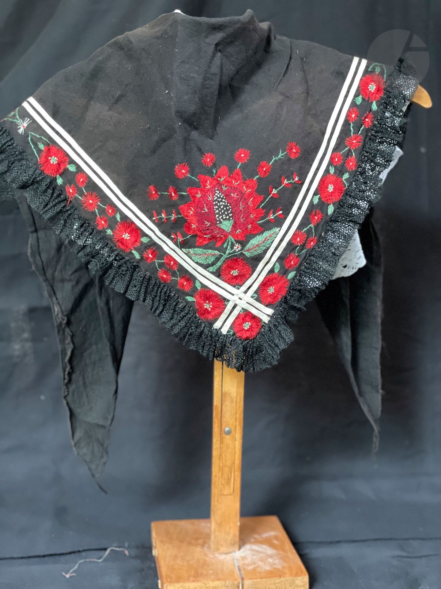 Fichu brodé pour fillette, Alsace, XIXe siècle. Belle broderie d'œillets rouge vif brodés en soie floche sur coton noir, galon blanc appliqué et petit volant de dentelle au crochet noir. *Modèle ayant servi pour un tableau reproduit en couverture du livre : Costumes d'Alsace, Etoffes d'un monde
On joint : une collerette linon et dentelle