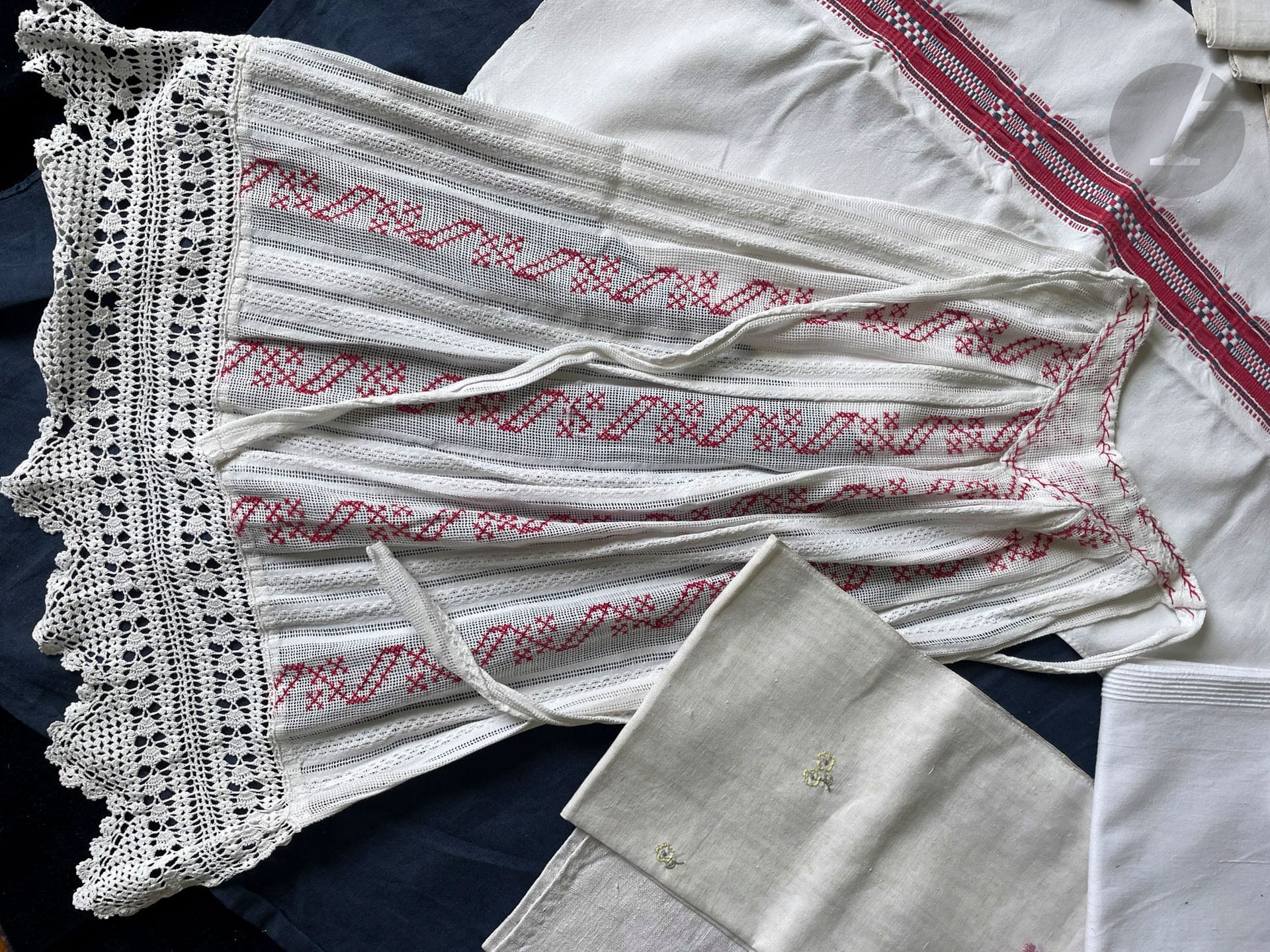 Réunion de 2 châles et un tablier de fête, pour jeune fille, Alsace 2e moitié du XIXe siècle en gaze de coton blanc brodé au point de croix et d'épine en fil rouge, ourlet dentelle rustique au crochet. Un tablier en soie noire à 2 étages rebrodé de perles de jais et fermée par cordelette de soie; le 3e en soie façonnée bouquets de fleurs vert et bleu sur fond noir