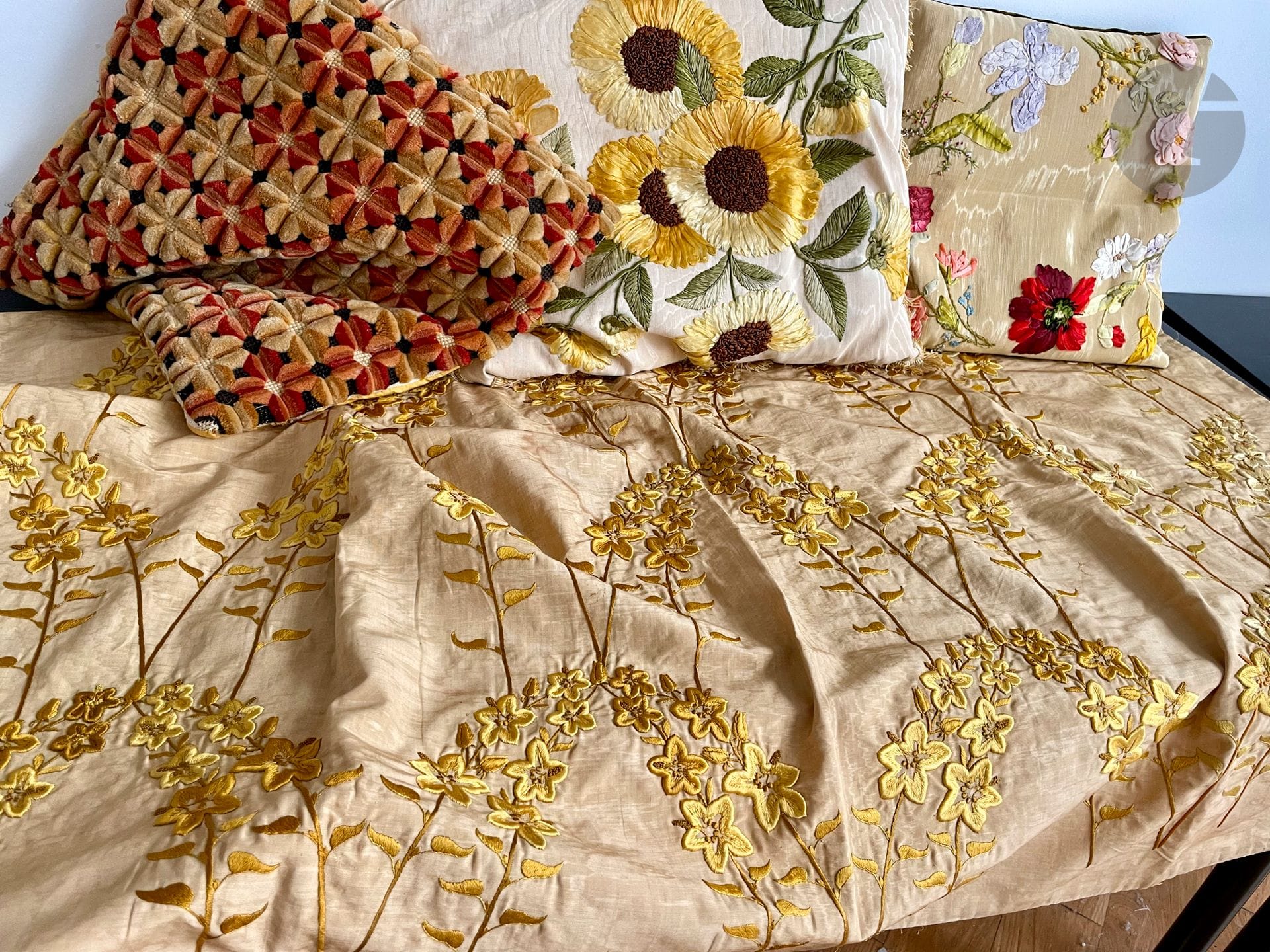 Réunion de 3 coussins et d'une tenture en broderie de soie or et rubans, début XXe siècle. Beau décor de tournesols ou fleurs variées sur moire de soie ivoire, doublé velours ; tenture moire brodée de fleurs de prunus en soie vieil or