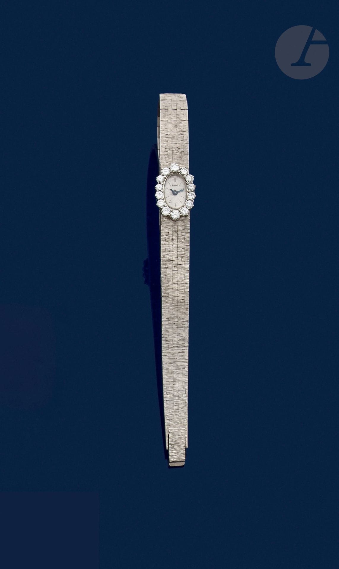 PIAGET pour JEAN ÉTÉ
Montre de dame en or gris 18K (750), cadran ovale serti de diamants ronds de taille brillant, fond guilloché, bracelet ruban souple en or gris 18K satiné. Signée et numérotée. Longueur : 16,5 cm environ. Poids brut : 41,2 g (fonctionnement non garanti)

A Piaget for Jean Eté lady's watch
