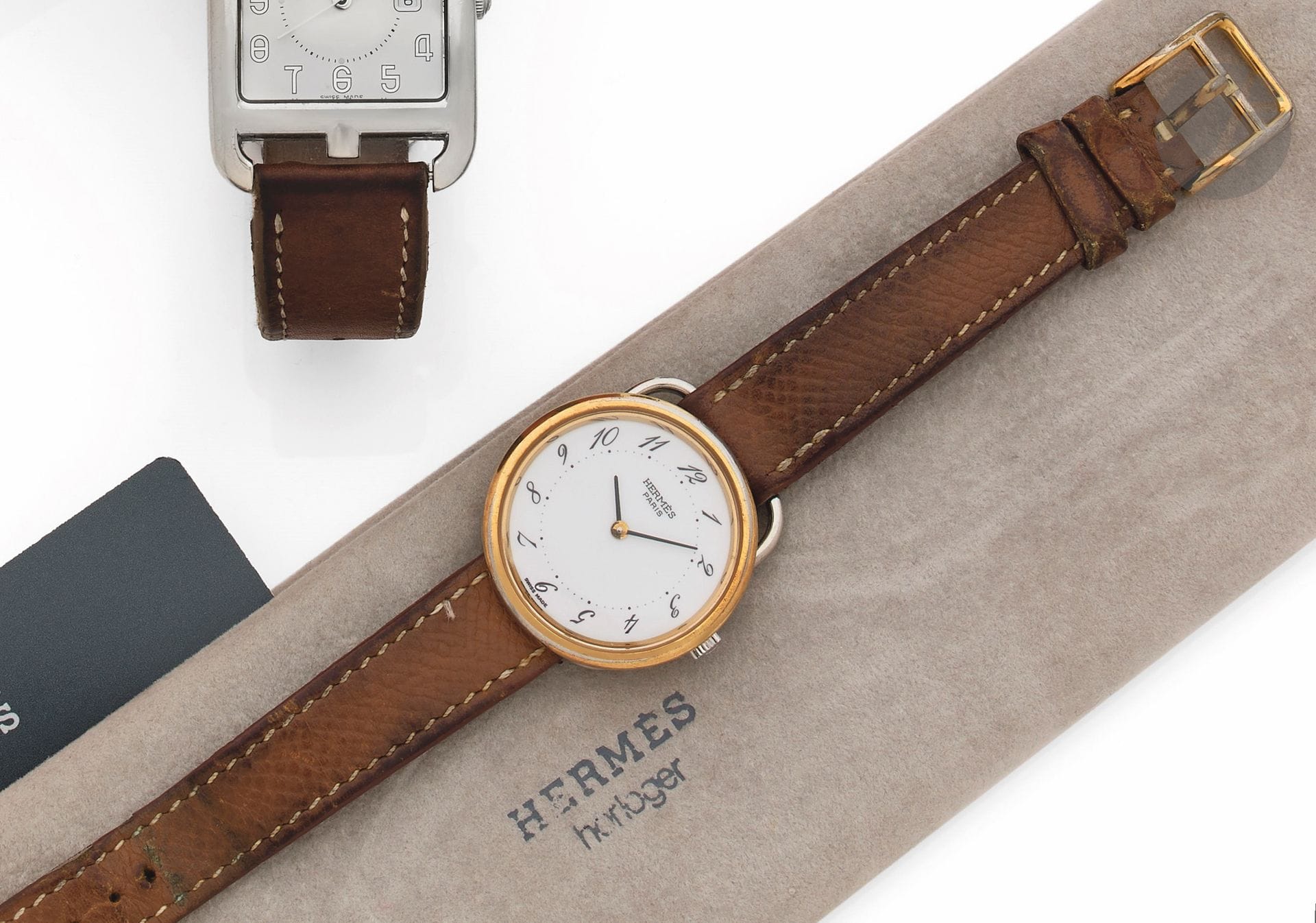 HERMÈS
ARCEAU
VENDUE EN 1989
Montre bracelet en acier et métal doré sur cuir.
Boîtier : rond en acier à larges attaches, lunette en metal doré. 
Cadran : blanc, index chiffres arabes peints.
Mouvement : quartz.
Bracelet : cuir avec boucle ardillon en métal doré, signés. 
Signée et numérotée 156130.
Diam. 30 mm 
Avec : pochette Hermès et certificat.