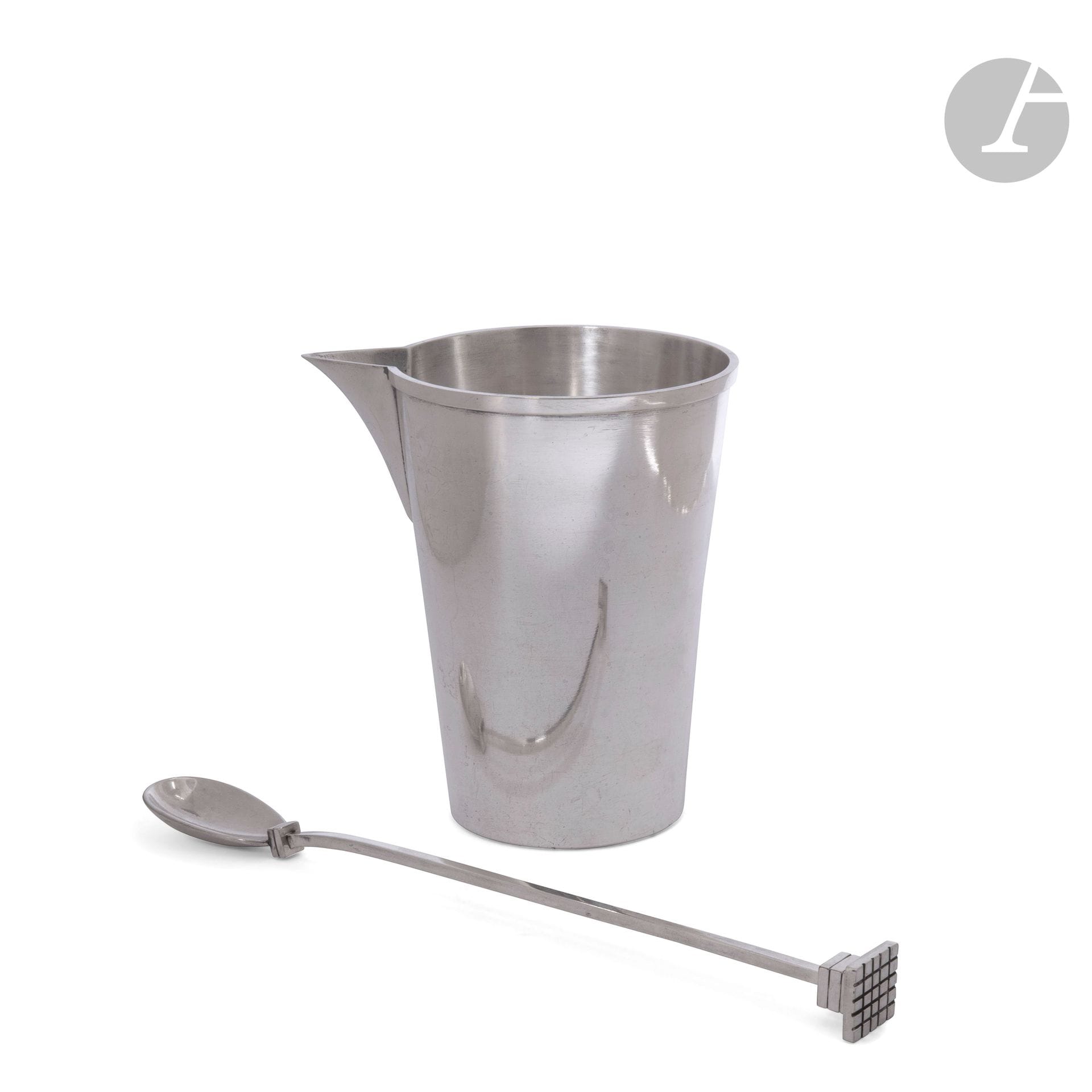 JEAN DESPRÉS (1889-1980)
Rare silver-plated cocktail pot with smooth surface, complete with stirring spoon. The flared body is adorned with rotating rushes on the rim. The spoon features two square rings above the spoon, and the grip is formed by a grooved block and topped by an overhanging square plate decorated with an engraved lattice. The pot is signed J. DESPRÉS at the point below the base. H.pot: 13.5cm - L.spoon: 25cm