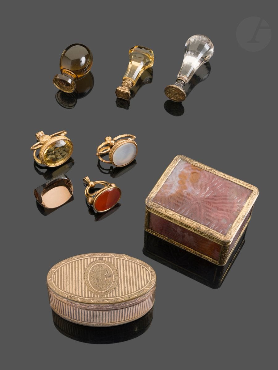 FRANCE 1819 - 1838
Lot de trois pierres: quartz laiteux, citrine taillée et cornaline montés en or 18 Kt formant breloques. On y joint un quartz fumé à trois pans destiné à être monté non gravée. 
Poinçon: têtes de bélier
Poids brut: 48g 
État: ancienne réparation aux deux couronnes