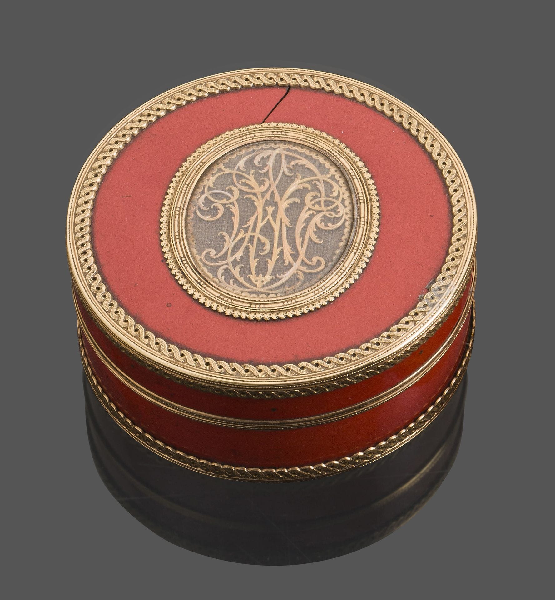 FRANCE 18th century
Circular tortoiseshell and coral lacquer box opening in half, the 18kt gold frame chased with a braid of interlacing flowers. In the center, on an oval gold medallion, is a motif of interlaced letters on a braided hair support. 
No hallmark of origin
Gross weight: 141g - diameter: 7.5cm
Condition: lacquer crack on the lid, on the side, missing on the reverse.
A blond tortoiseshell frivolity shuttle with gold inlays is included.
Length: 11.3cm - width: 3.7cm
Condition: numerous moth holes and missing gold inlays