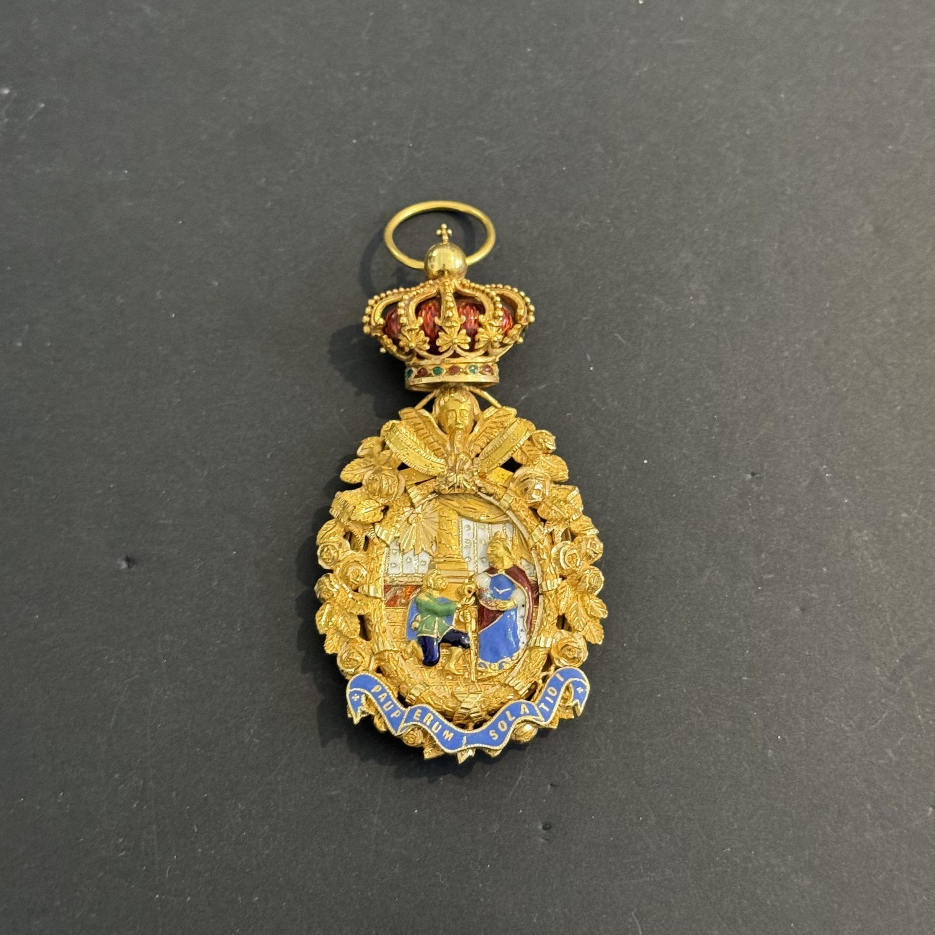 PORTUGAL 
ORDRE ROYAL DE SAINTE ISABELLE
Rare et bel insigne de dame de l’ordre. 
En or richement ciselé de roses, rubans et angelots, le médaillon central émaillé. L’ensemble sous couronne royale perlée à cœur émaillé rouge. 
Anneau lisse. 
90 x 46 mm - Poids brut : 68 g
T.T.B. (infimes éclats).

Lot vendu sur désignation, retrait disponible le vendredi 06 décembre.