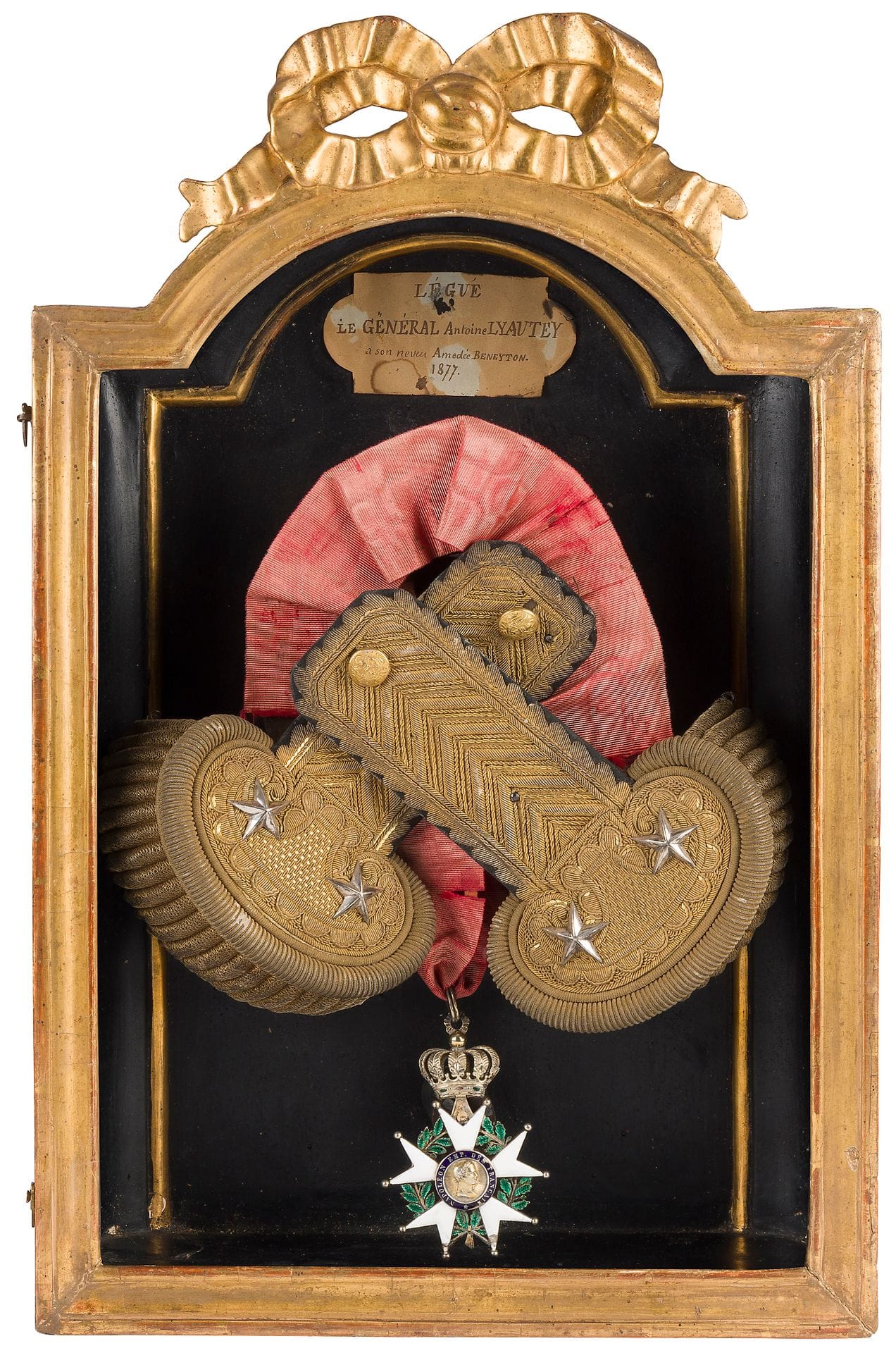 FRANCE 
ORDRE DE LA LÉGION D’HONNEUR 
Ensemble de souvenirs du général Antoine LYAUTEY comprenant : 
- une paire d’épaulettes de général de brigade, d’époque IIe République. En passementerie dorée. Boutons au modèle des généraux (au coq). 
- une croix de commandeur d’époque Présidence. En vermeil et émail (éclats). Avec cravate.
L’ensemble présenté encadré sous verre dans un cadre doré avec cartouche à la plume « LEGUE LE GENERAL ANTOINE LYAUTEY SON NEVEU AMEDEE BENEYTON 1877 ».
A.B.E. 

Antoine LYAUTEY (1794-1877) : oncle du futur maréchal, général de Brigade, nommé commandeur de la Légion d’honneur en mai 1852. 

Charles Amédée BENEYTON (1824-1888) : son neveu, était camérier Secret de Cape et d’Épée de S. S. le Pape Léon XIII.