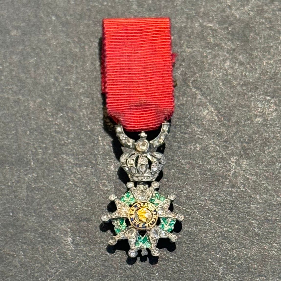 FRANCE 
ORDRE DE LA LÉGION D’HONNEUR 
Étoile de chevalier, miniature, modèle de luxe, garni de diamants, d’époque Second Empire. 
En argent, or et émail, richement garni sur l’avers de petits diamants. Traces de poinçon sur l’anneau. Ruban à passant d’attache. 
21 x 11 mm - Poids brut : 2,1 g
Dans son écrin gainé de velours en forme. 
T.T.B. à SUP.