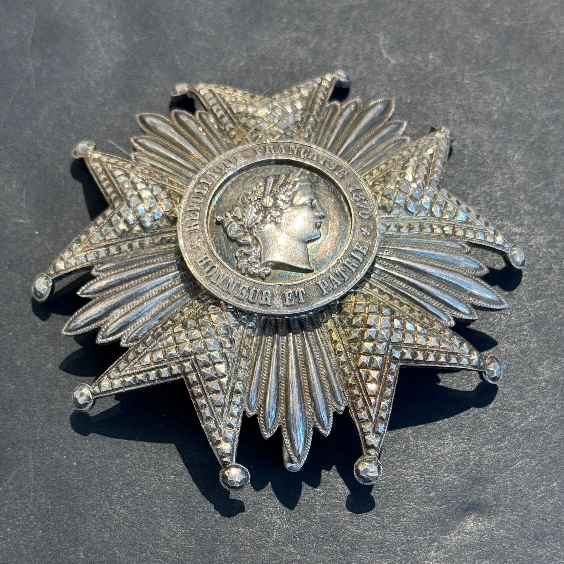 FRANCE
ORDRE DE LA LÉGION D’HONNEUR, institué en 1802. 
Plaque de grand-croix d’époque IIIe République. 
En argent, en partie travaillé à pointes de diamant (petits coups aux pointes). Revers à agrafe basculante et deux crochets. Poinçon tête de sanglier et d’orfèvre Arthus Bertrand. 
91 mm - Poids brut : 110 g
T.T.B.