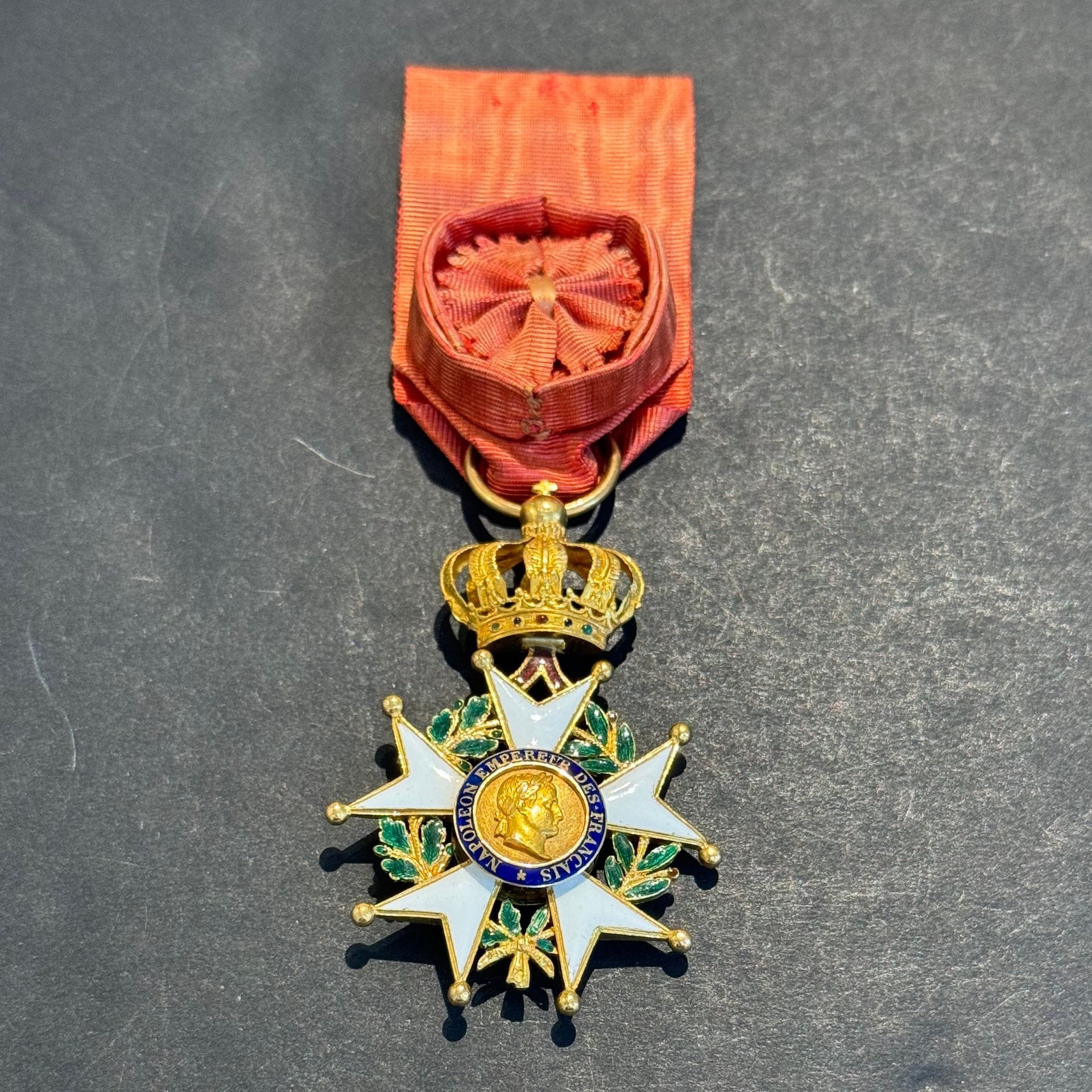 FRANCE 
ORDRE DE LA LÉGION D’HONNEUR. 
Étoile d’officier d’époque Second Empire, fabrication soignée de bijoutier, à filets. 
En or ciselé et émaillé (petits cheveux et éclats, deux boules faussées). Centres en trois parties. Poinçon tête d’aigle.
64 x 42 mm - Poids brut : 20,3 g
Ruban à rosette ovoïde. 
T.B. à T.T.B.