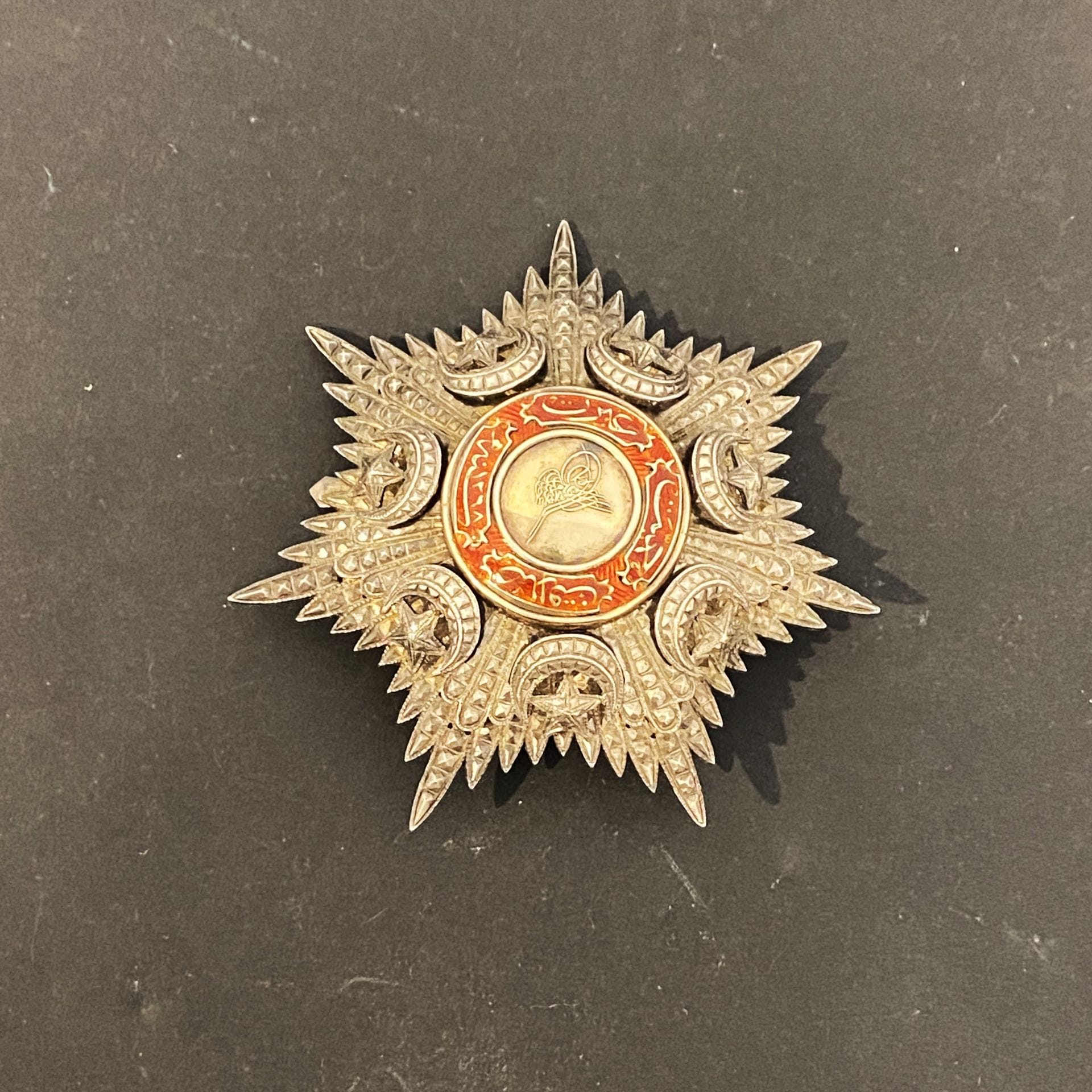 EMPIRE OTTOMAN
ORDRE DU MEDJIDIÉ
Plaque de grand officier. 
En argent travaillé à pointes de diamant sur deux niveaux. Centre en or émaillé. Revers à deux crochets et attache basculante, avec poinçon de fabrication locale.
72 mm - Poids brut : 64 g

Lot vendu sur désignation, retrait disponible le vendredi 06 décembre.