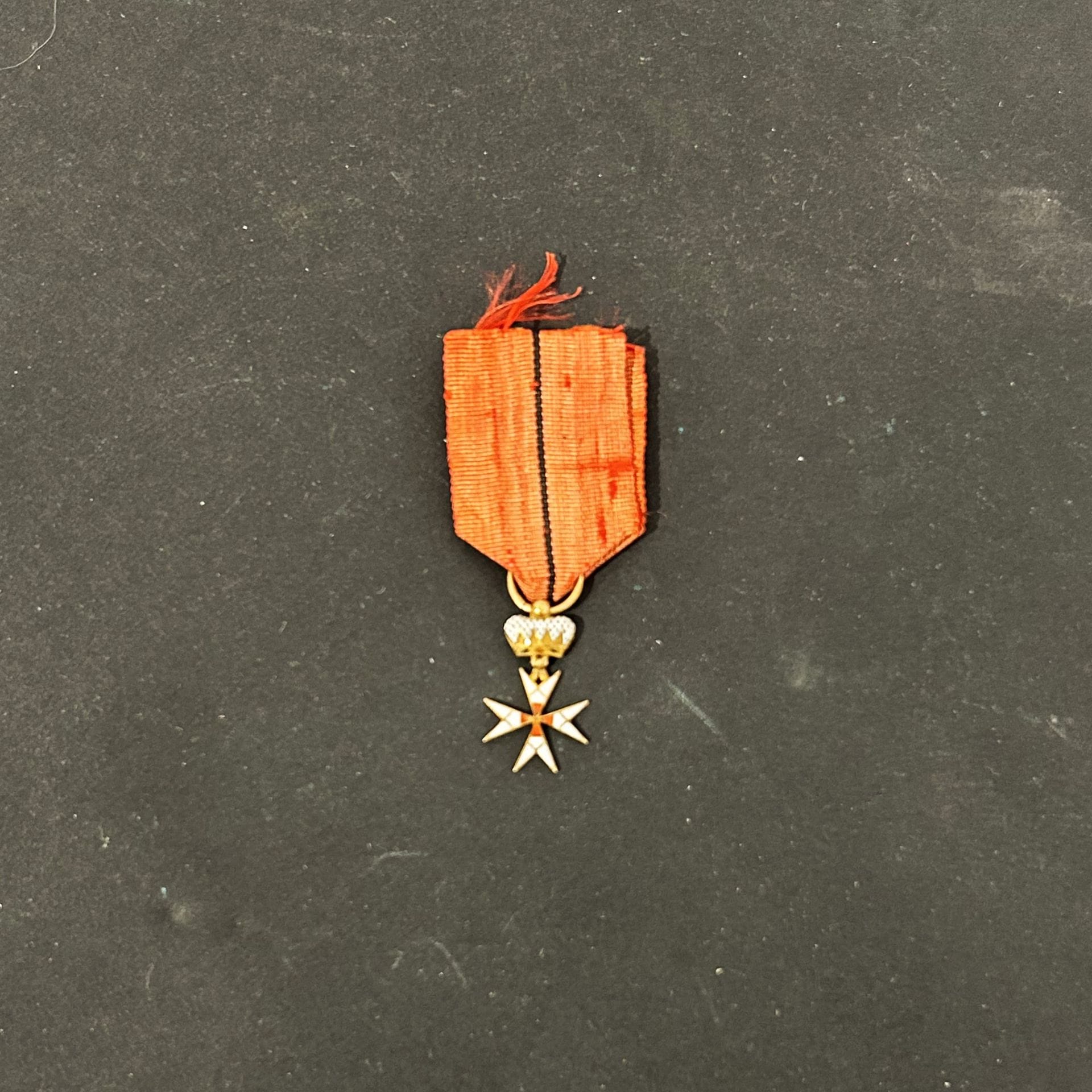 FRANCE 
ORDRE DU TEMPLE, réinstitué en 1804. 
Croix de chevalier, miniature. 
Croix en or émaillé blanc et rouge (petit éclat), surmonté d’une couronne en émail peint. Anneau lisse. 
Petit ruban à filet central noir. 
21 x 15 mm - Poids brut : 2,1 g
T.T.B.
Début du XIXe siècle