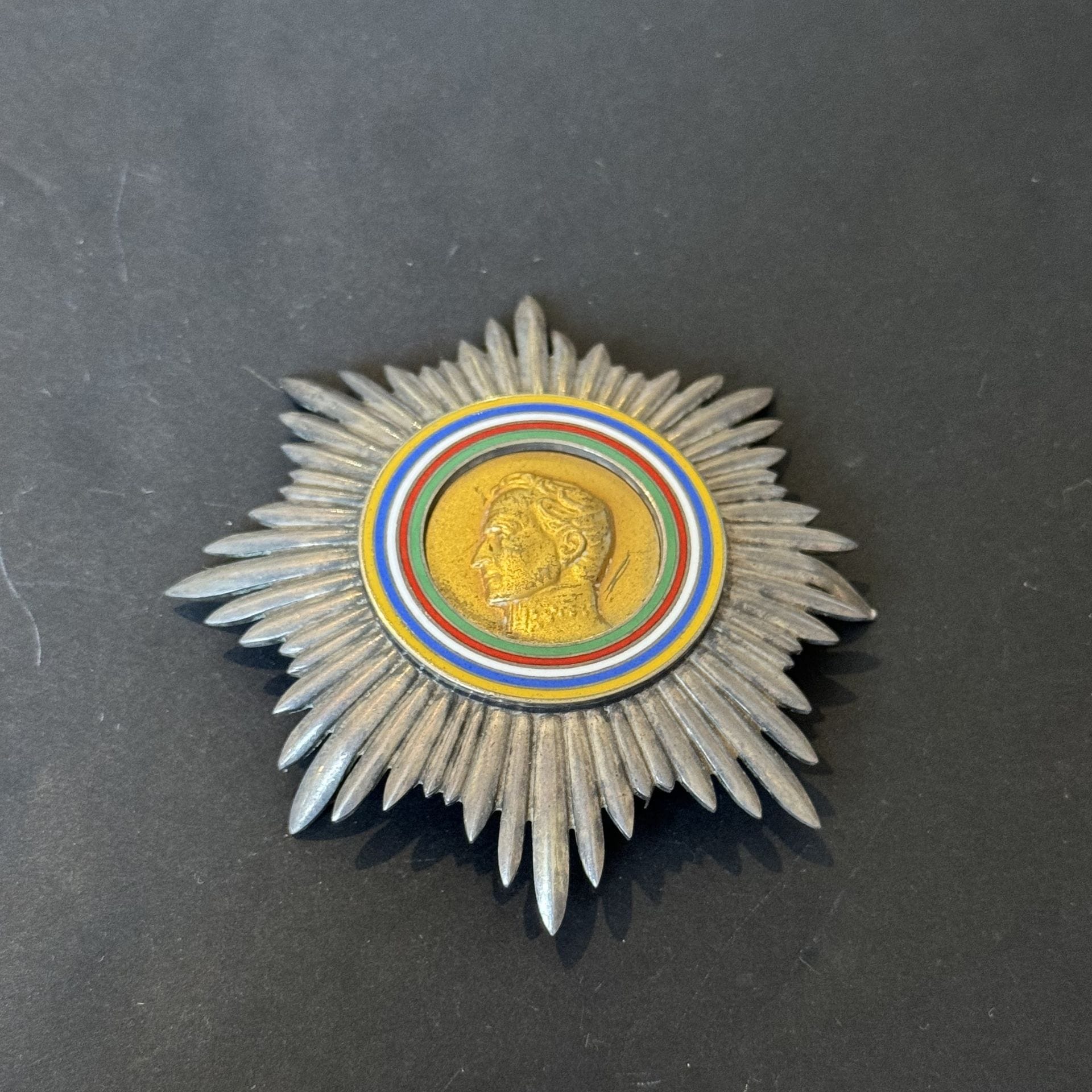 BOLIVARIAN SPORTS ORDER 
Silver plaque with gilded center featuring the profile of Simon BOLIVAR and four-color enameled legend. 
Reverse with two pins and loop. Hallmarked by the Maison Huguenin and titled 0.925. 
85 mm - Gross weight: 74 g
T.T.B.