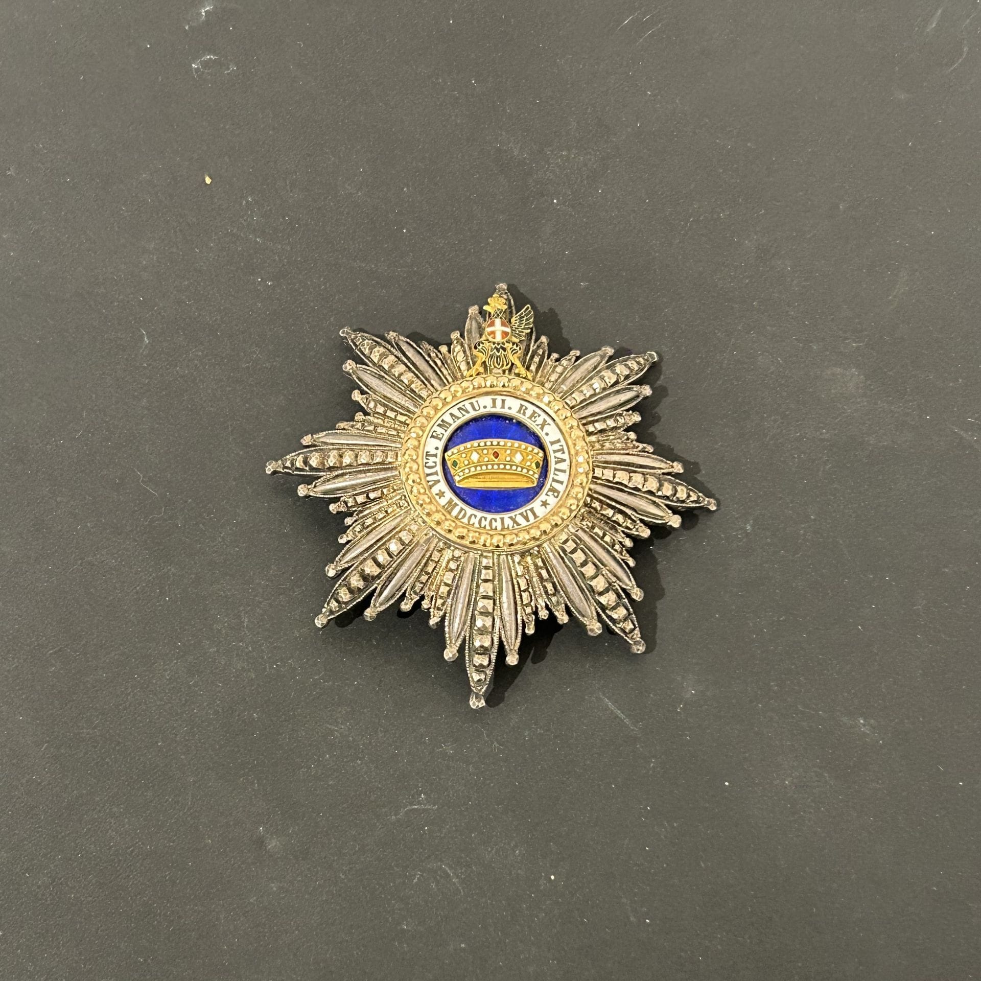 ITALY
ORDER OF THE CROWN OF ITALY
Grand Cross plaque.
Silver and vermeil (one wing of the eagle is missing). Central gold crown. Reverse side with toggle clasp (significant trace of glue in place of the maker's mark).
Diameter: 87 mm - Gross weight 82 g
T.B.

Lot sold by appointment, collection available on Friday December 06.