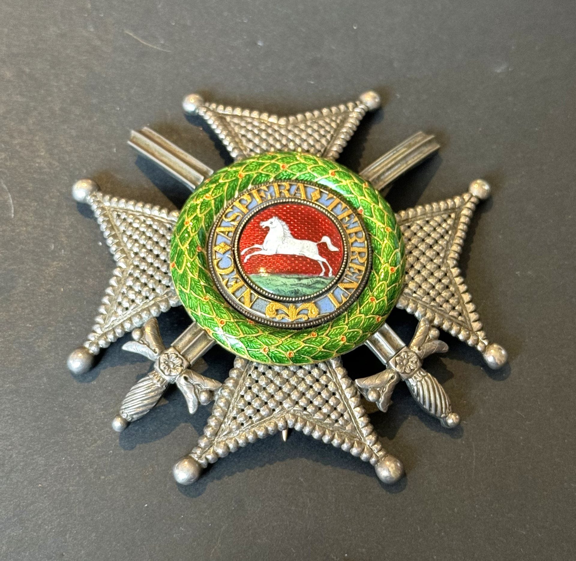 GERMANY (HANOVER) 
ORDER OF THE GUELPHS 
Rare military grand-cross plaque. 
Silver, worked with diamond points and swords. Gold center with green enameled laurel wreath, openwork legend NEC ASPERA TERRENT. Reverse with toggle clasp and gold hook, signed "RUNDELL BRIDGE &amp; RUNDELL JEWELLERS TO THEIR MAJESTIES His Royal Highness the Prince Regent and the Royal Family".
87 mm - Gross weight: 76 g
T.T.B. Circa 1815-1820.