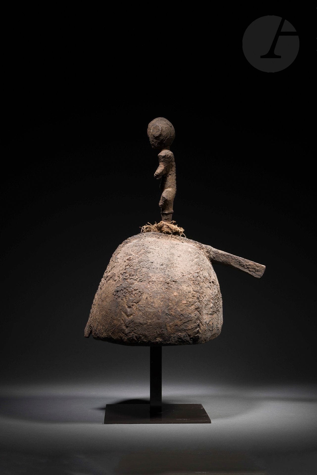 Un rare et très ancien casque relevant d’un corpus aussi rare que peu documenté. Le personnage amovible fixé à son sommet est cependant caractéristique de la statuaire Keaka (sud-est de la Cross River): volumes épannelés, buste cintré prolongé par des bras courts aux mains esquissées, visage résumé à la bouche entrouverte, striée de dents. Au même titre, l’épaisse patine sombre et croûteuse qui l’enveloppe, témoin de son importance cultuelle et de son ancienneté, constitue l’un des signes distinctifs de cet art. Selon Viviane Baeke, les masques-casques Keaka interviendraient dans le contexte du rite médicinal so, renvoyant à un être spirituel exceptionnel (cf. Lebas, Arts du Nigeria dans les collections privées françaises, 2012, p.287).
Keaka, Cameroun
Bois dur, accidents et petits manques visibles anciens, superbe et ancienne patine de suie et d’usage.
H.: 43,5cm

Provenance:
Galerie Argile, Paris, 1970
Sotheby’s, Paris, 21 juin 2017, n°40
Collection Hélène Leloup, Paris
Transmis par descendance