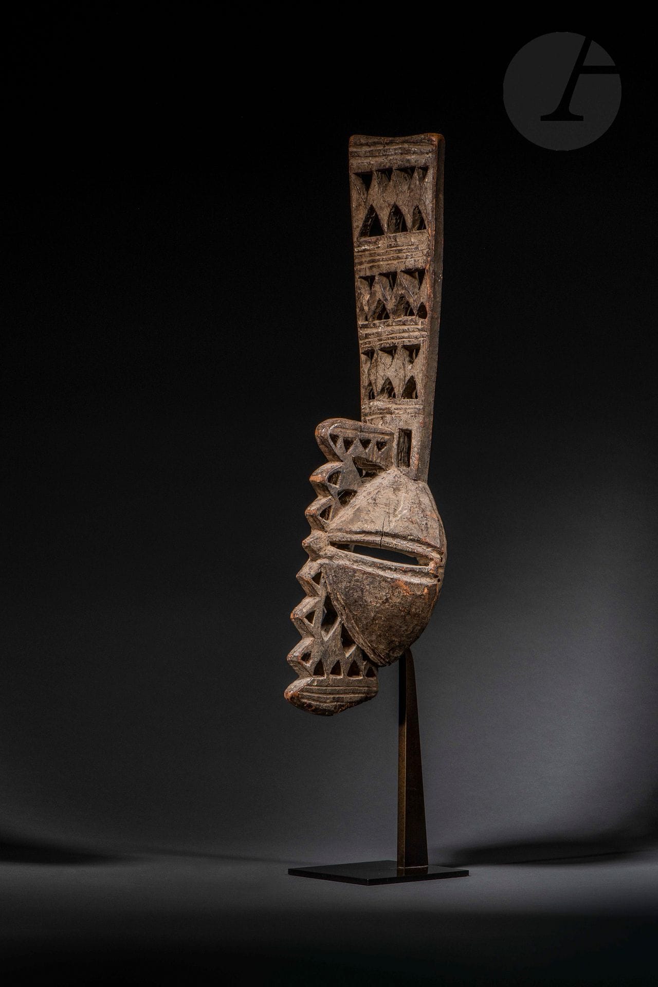 Un très ancien masque dédié aux mascarades okumpkpa du groupe Ada et participent aux célébrations des initiations masculines. Ce masque «incarne dans la pensée Igbo la force masculine et l’originalité». Sa conception, avec ses grands yeux fendus, et ses deux plans (axial et frontal) qui s’entrecroisent ornés de décors géométriques ajourés en font un des masques les plus fascinant de tous les arts du Nigéria, et au-delà. 
Voir pour deux autres très beaux exemplaires anciens comparables: Arts du Nigéria dans les collections française, Lebas, 2012 n°91 et Igbo Arts Community and Cosmos, Cole & Aniakor, 1984, p.115 n°215.
Igbo-Afikpo, Nigeria, fin XIXe - début XXe siècle
Bois dur, usures et petits manques (casse ancienne), très belle oxydation d’ancienneté, et ancienne très belle patine d’usage.
H.: 61cm

Provenance:
Jean-Pierre Laprugne, Paris
Enchères Rive Gauche, 8 septembre 2011, n°134
Collection Stéphane Kurc, Paris