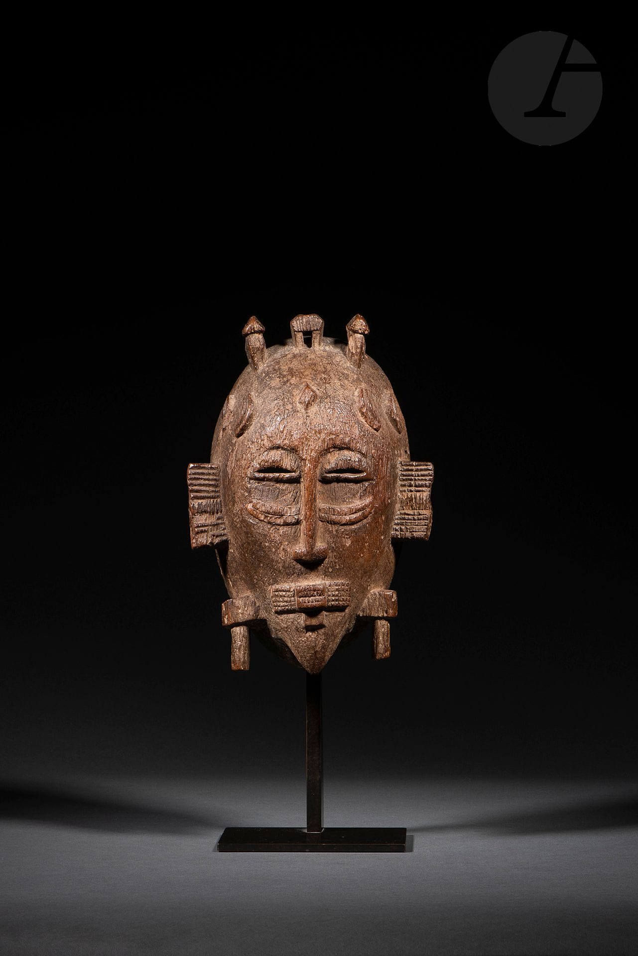 Un ancien masque kpelie, masque de la société masculine du Poro. Timothy Garrard (dans Arts de la Côte d’Ivoire, 1993, p.87) place tôt dans l’évolution stylistique des masques Sénoufo ceux dont les appendices ne dépassent que de très peu la ligne du menton, comme c’est clairement le cas ici. Ce masque est en effet très ancien, cependant cette remarque de Timothy Garrard ne peut être érigée en règle générale et doit valoir pour certains cercles.
Sénoufo, Côte d’Ivoire
Bois dur, usures et légères fentes d’ancienneté, très belle érosion d’ancienneté et très belle patine d’usage. 
H.: 24cm

Provenance:
Jean Paul Delcourt, Abidjan
Enchères Rive Gauche, Paris, 8 septembre 2001, n°146
Collection Stéphane Kurc, Paris