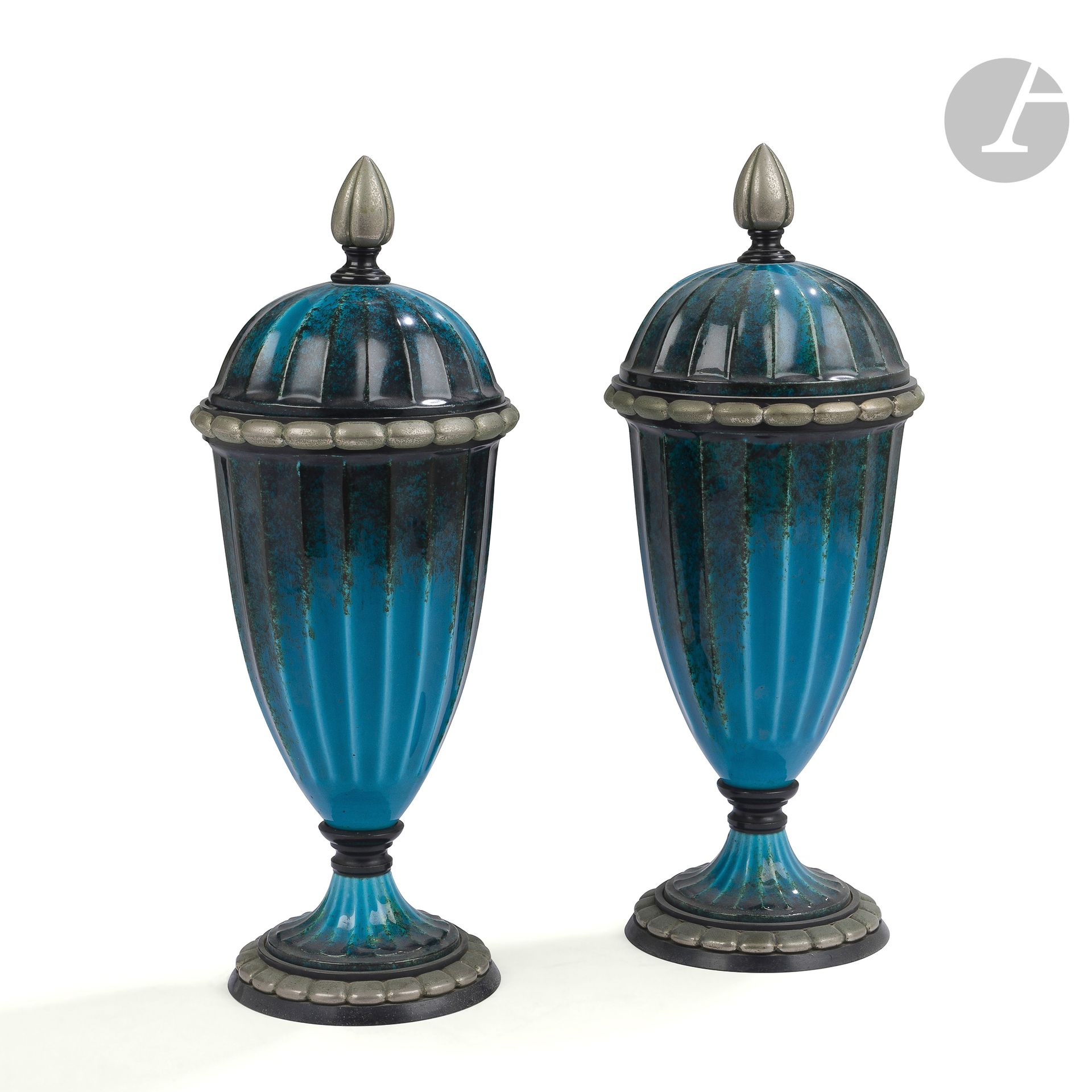 PAUL MILLET (1870-1950) CÉRAMIQUES D’ART À SÈVRES
Importante paire d’urnes facettées, couvertes et montées. Épreuves en céramique émaillée bleu canard; les bases, les pourtours et les prises en métal. Chacune complète de son intérieur. Époque Art déco. Défauts de cuisson. Un couvercle monogrammé M. P. Sèvres au revers. H. 37,5 cm