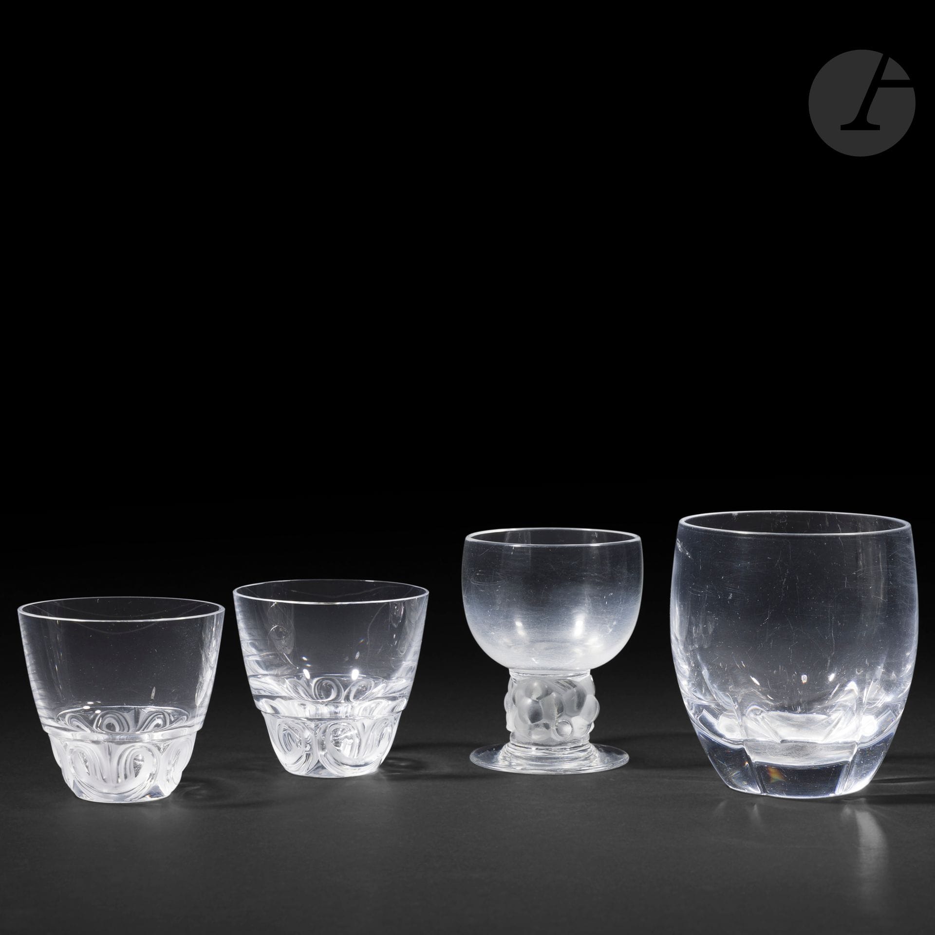 RENÉ LALIQUE (1860-1945) ET MARC LALIQUE (1900-1977) ET MAISON LALIQUE
Ensemble de 4 verres différents composé comme suit: 
- Thomery, le modèle conçu en [1931]
Un verre à Bordeaux n° 4 (Réf. Marcilhac 5255).
Épreuve en verre blanc soufflé-moulé pour le corps et moulé-pressé et, en partie satiné pour la base.
Signé R. Lalique France sous la base. 
- Highlands
Un verre à whisky.
Épreuve en cristal soufflé-moulé.
- 2 gobelets à décor de volutes en relief.
Épreuves en cristal soufflé-moulé et, en partie, satiné.
Chaque pièce signée Lalique ® France en lettres cursives, à la pointe, sous la base. 
Hauteurs: 9 – 10,2 cm – 7,1 cm
