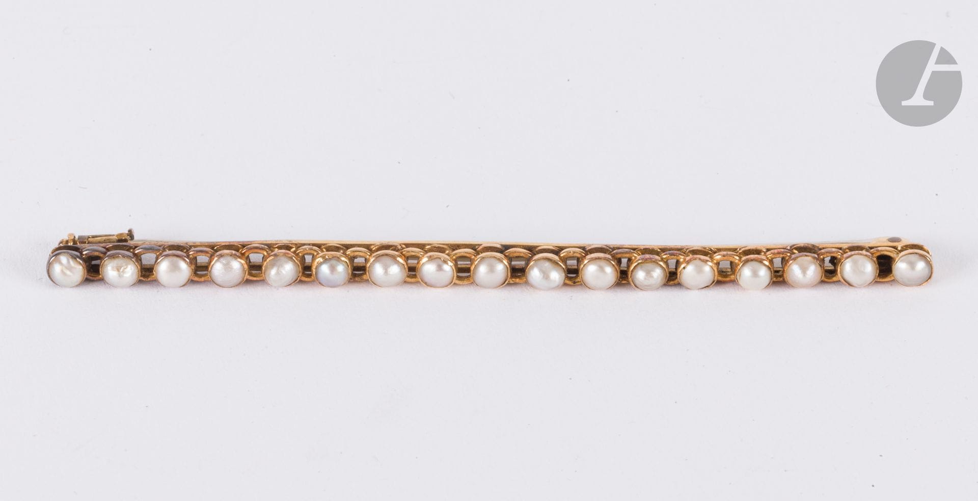 Broche en or 18K (750), formée de quatre ovales, chacun orné de demi-perles dans un entourage émaillé. Longueur : 5 cm environ. Poids brut : 5,8 g (manque à l'émail, transformation)