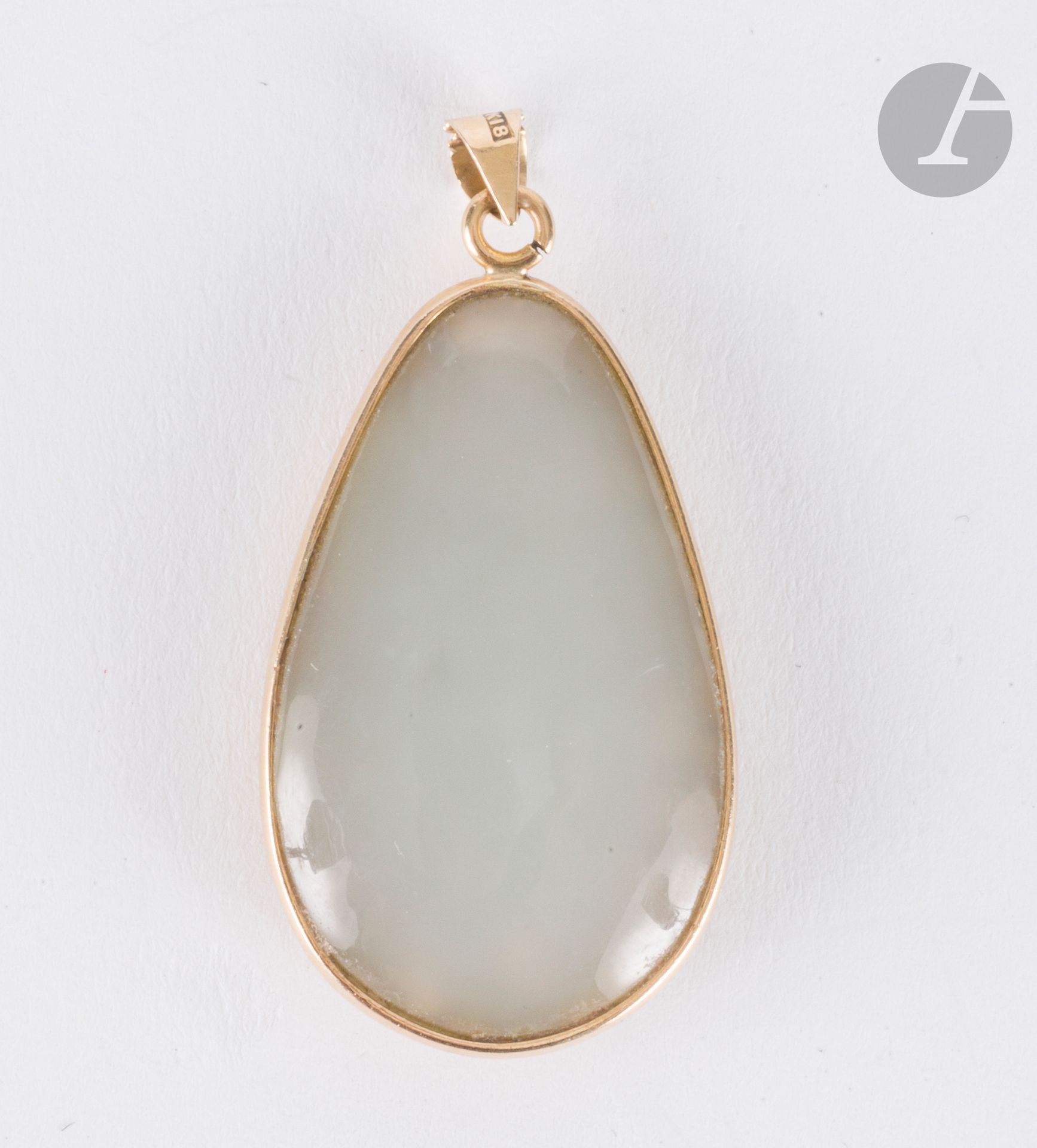 Pendentif en or 18K (750) serti d'un jade gris pâle cabochon, le revers repercé et gravé d'un dragon dans des nuages. Hauteur : 3,2 cm environ. Poids brut : 7,1 g