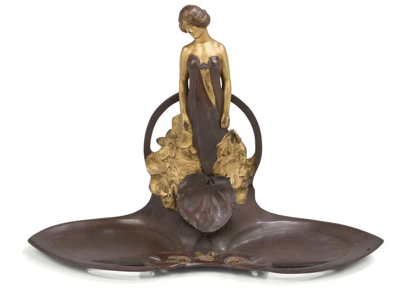 CHARLES KORSCHANN (1872-1943) Jeune femme pensive Encrier à deux plumiers; la figure titre traitée en ronde-bosse. Épreuve en bronze à double patine; chocolat, or. Époque Art nouveau. Absence du l’encrier en verre. Signé Ch. KORSCHANN et porte le cachet LOUCHET Paris Ciseleur à la base au dos. H. 24 cm u L. 35 cm