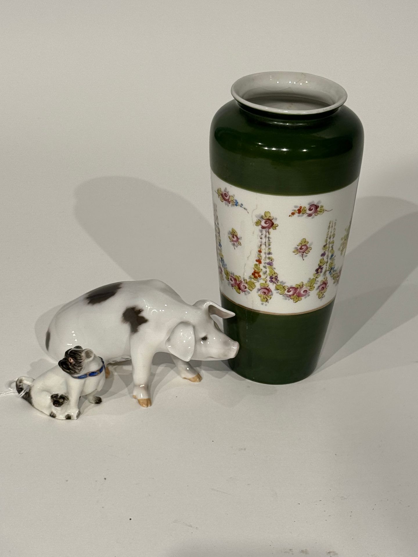 Lot including: 
ROYAL COPENHAGEN, Two porcelain subjects:
- one representing a pig (7 x 13 x 5 cm), marked Royal Copenhagen under the base
- the other depicting a pug and its cub (5 x 5.5 x 3 cm)
&
SEVRES
Porcelain vase decorated with garlands of flowers and wicker baskets in a frieze on a green ground.
19th century.
Mark with 2 interlaced Ls in blue under the base.
Height: 19 cm