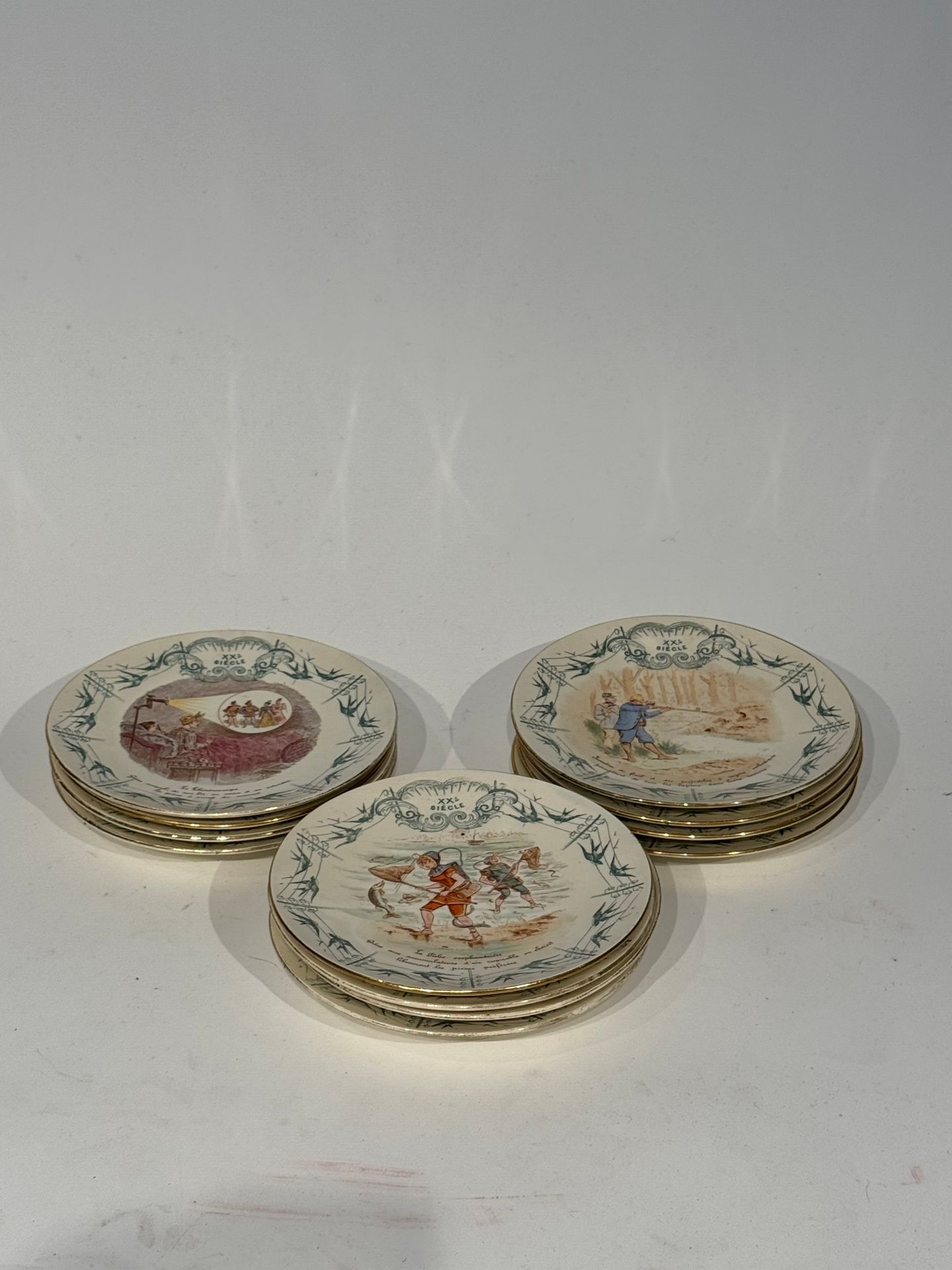 K&G LUNEVILLE
Suite de 12 assiettes à dessert en faïence à décor humoristique, modèle "XXe siècle". 
D. 20 cm