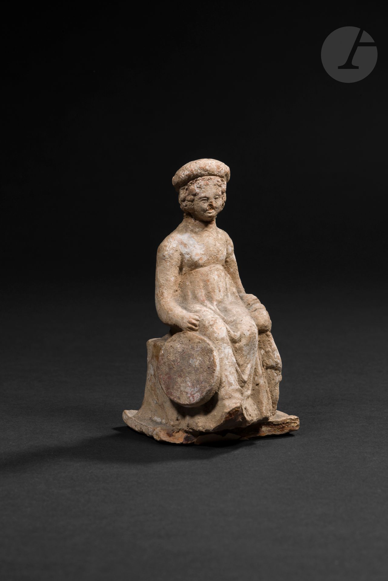 Statuette figurant une jeune fille assise
Elle est vêtue d'un drapé et coiffée d'un bonnet. Elle tient une cymbale (tympanum). Ancienne étiquette des douanes de Paris Gare de Lyon Bercy.
Terre cuite. Cassée-collée.
Art grec, IV-IIIe siècle avant J.-C. 
Hauteur : 10,2 cm 

Provenance : 
- Roussos et Moïse Zoumpoulakis, avant 1926.
- Galerie Brummer, inv. A131 (acquise en 1926).
- Piero ( ?) Tozzi (acquise le 7 mars 1949).
- Collection privée belge, puis par descendance.

https://libmma.contentdm.oclc.org/digital/collection/p16028coll9/id/61328/rec/40