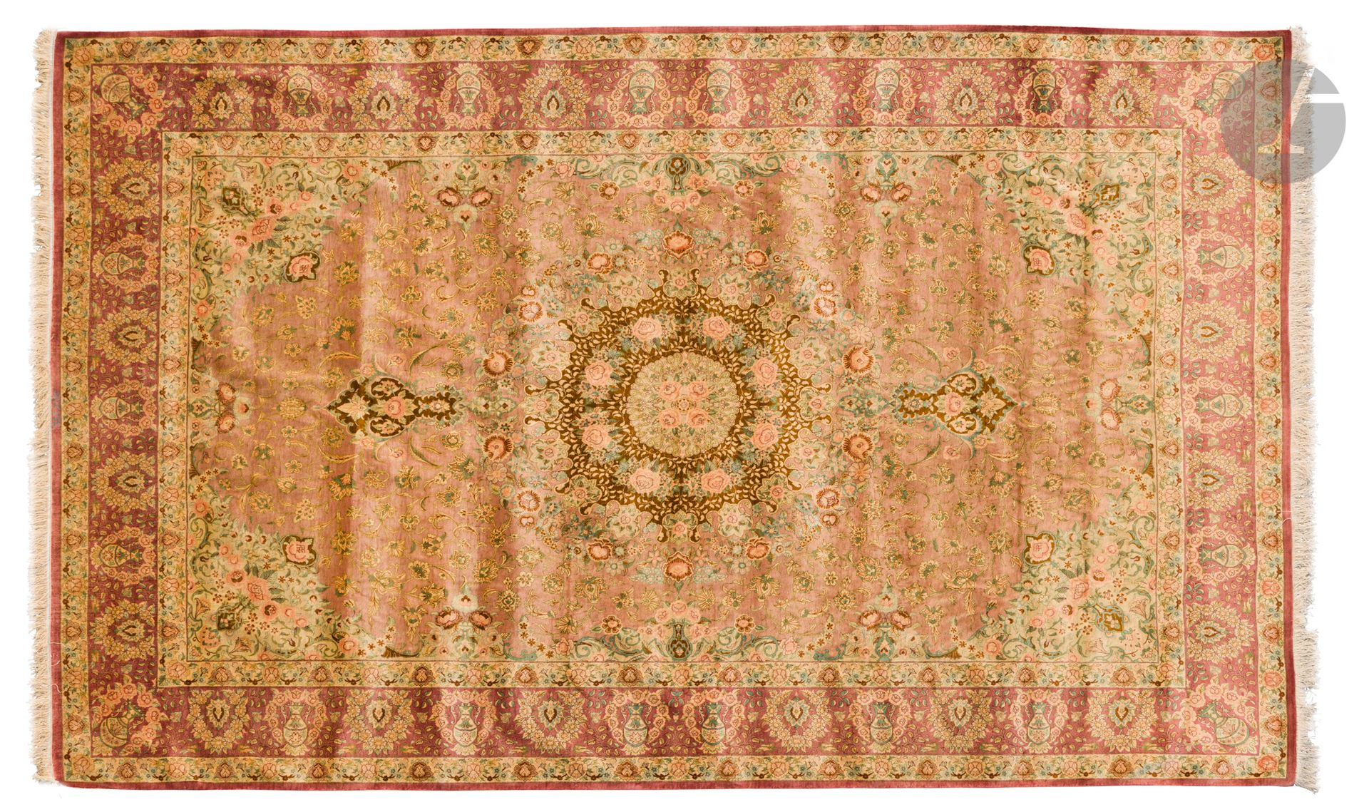 Tapis Ghoum, XXe siècle 
Velours, chaîne et trame en soie. Très fin tapis à décor de motif central polylobé sur un fond vieux rose à rinceaux fleuris et écoinçons verdeux à bouquet de roses. Large bordure lie de vin à vases fleuris. Signé à l'extrémité. 
315 x 200 cm