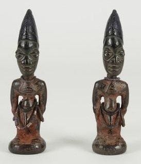 YOROUBA (Nigéria) Paire d'Ibedji. Statuettes de sexe masculin pour le culte des jumeaux, style d'Igbomina. Recouvertes de terre orée rouge et de teinture bleue. Bracelets et colliers de perles multicolores, bracelet de bronze. Inclusions de clous dans les yeux. Belle patine d'utilisation. H.: 30 cm
