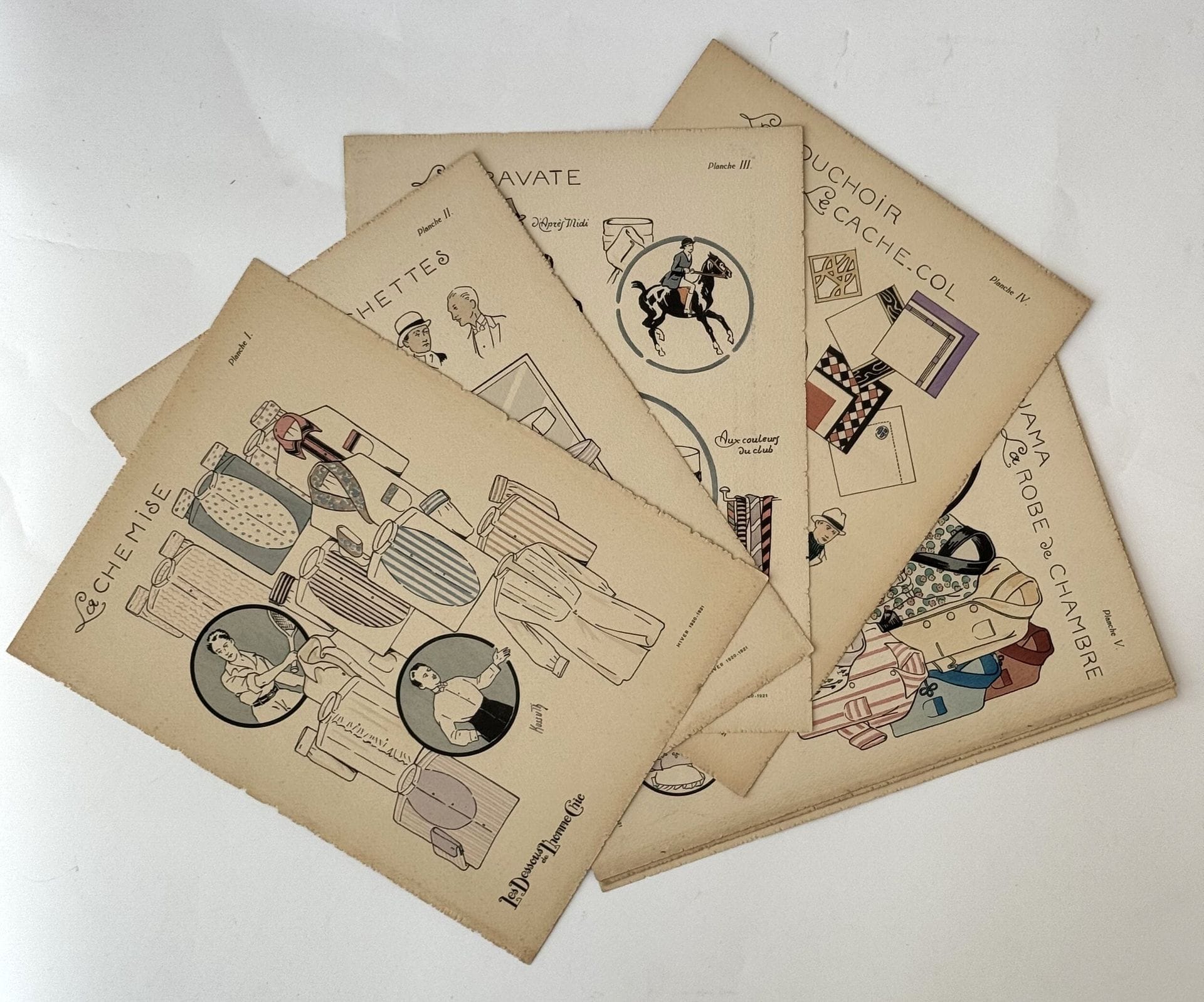 [REVUE MASCULINE].
Les Dessous de l’homme chic.
Paris : imprimerie Kossuth, 1920-1921. — 3 albums in-4, 323 x 245. En feuilles, sous chemise à rabat, en papier grainé gris foncé imprimé.

L’éditeur Kossuth, qui publiait déjà L’Homme chic, propose dans cette publication semestrielle des dessous, des chemises et des accessoires.

Cet ensemble contient 19 planches au pochoir, dont 8 (sur 10) pour la saison Hiver 1920-1921, 5 planches pour la saison Printemps-été 1921 et 6 planches pour la saison Hiver 1921-1922.

Une très rare revue masculine.