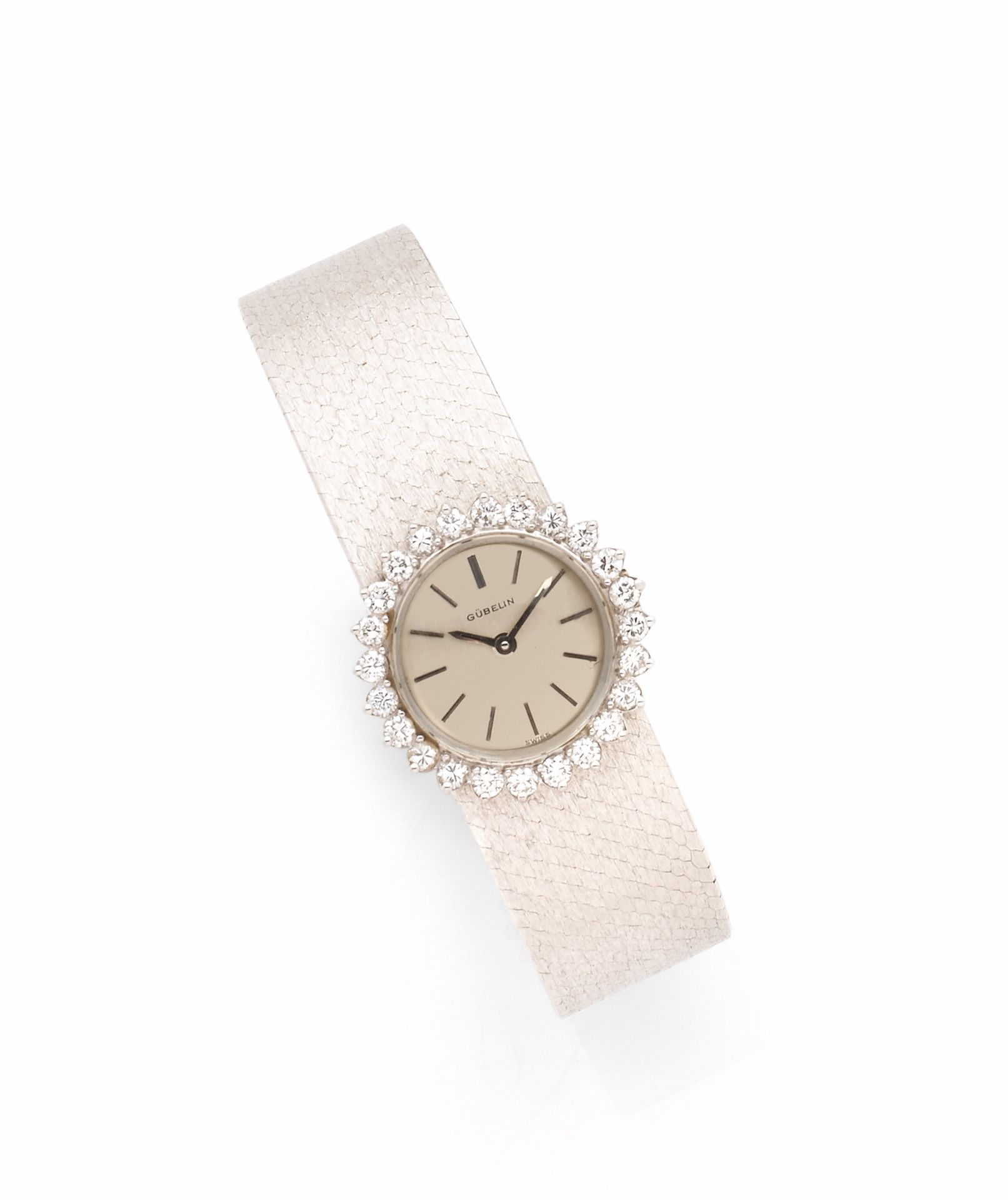 GUBELIN
ANNÉES 60
Montre bracelet de dame en or gris 18K (750) et diamants.
Boîtier: rond, lunette sertie de diamants.
Cadran: argenté, index bâton appliqués.
Mouvement: mécanique.
Bracelet: or gris satiné, boucle simple, siglée.
Cadran, boîtier et mouvement signés. 
Numérotée 
Diam. 20 mm 
Poids brut: 40,5g