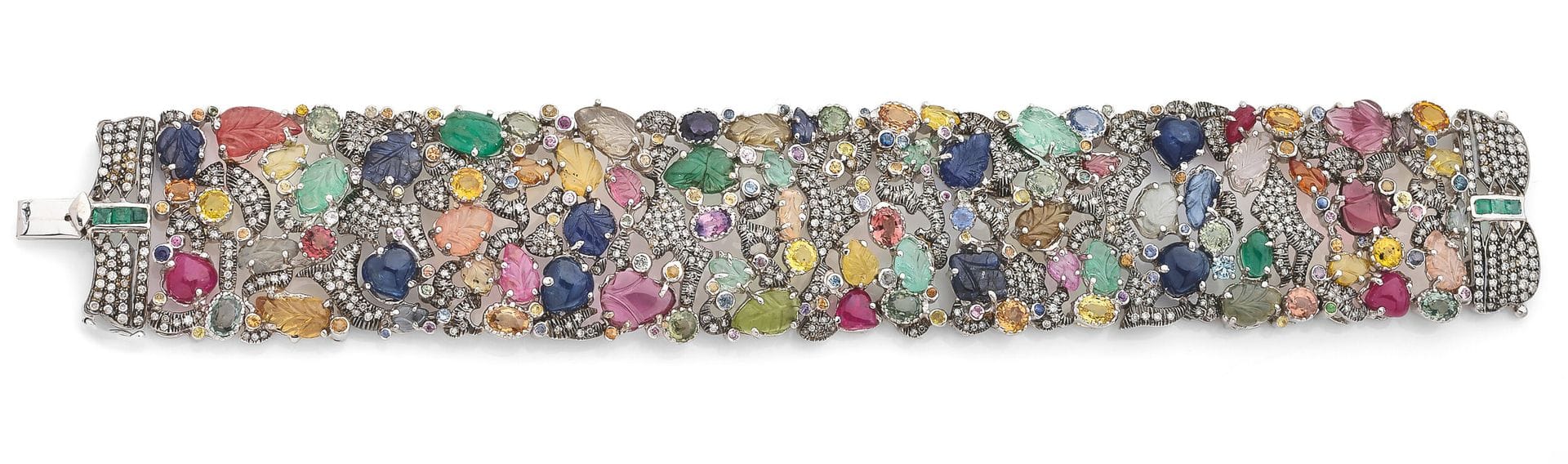 Bracelet ruban en or gris 18K (750) serti de diamants ronds de taille brillant, orné de feuilles sculptées en rubis, en saphirs, émeraudes ou pierres de couleurs variées, agrémenté d’autres pierres de couleurs cabochons ou facettées. Travail indien moderne. Dimensions: 19x3cm environ. Poids brut: 72,7g (égrisures, chocs, manques)
An Indian modern bracelet
