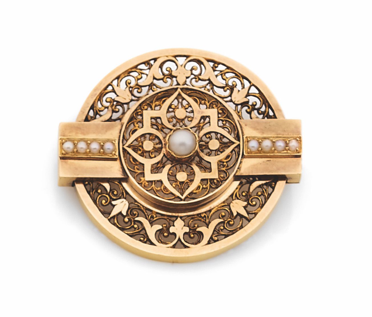Broche ronde en or 18K (750) repercé de rinceaux, ornée de demi-perles. Travail de la seconde moitié du XIXe siècle. Diamètre: 3,7cm environ. Poids brut: 14,4g
A late 19th  century brooch