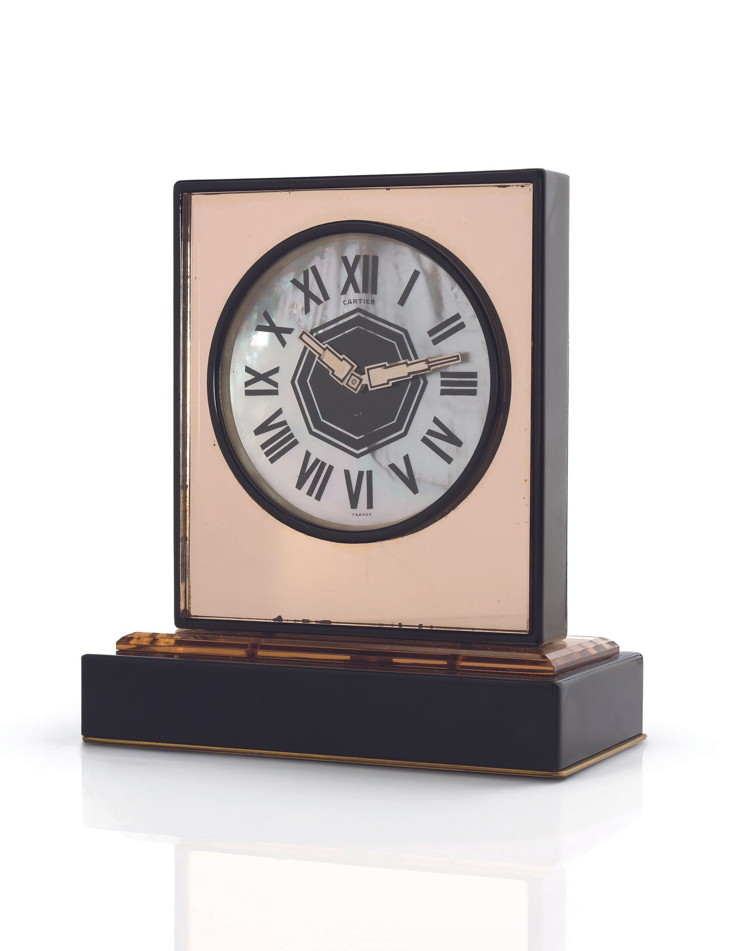 CARTIER France
ANNÉES 30
Pendulette en laiton doré, laqué noir, nacre, miroir et cristal de roche’ fumé’  d’époque Art Déco.
Boîtier: rectangulaire miroir fumé avec ouverture circulaire pour le cadran, dans un encadrement laqué noir. 
Socle laqué noir sur plaque de laiton doré, sur une base en cristal de roche biseauté.
Cadran: circulaire en nacre, index chiffres romains émaillés noir et motif polygonal noir au centre, aiguilles acier ‘Art Déco’, signé Cartier France.
Mouvement: mécanique.
Numérotée 6487.
Largeur: 13,5cm, profondeur: 7cm, hauteur: 15cm
 
Un modèle identique dans la vente Jewellery by Cartier, Christies, Genève, 21 mai 1992, lot 648, p. 97.