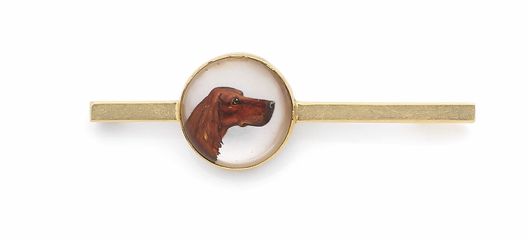 Broche-barrette en or 18K (750), ornée d’un verre Essex peint d’un protomée de chien de chasse. Travail de la fin du XIXe siècle. Diamètre du motif: 1,5cm environ. Poids brut: 7,2g
A late 19th  century Essex glass brooch