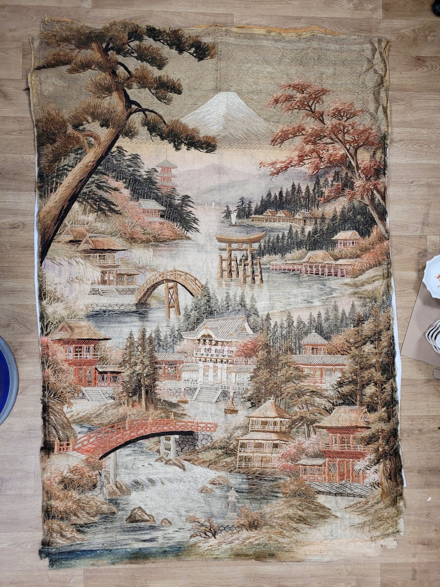 Large ornamental hanging, Japan, Meiji period
Embroidered on a cotton ground of silk, cotton and metallic threads of a large architectural landscape, crossed by a torrent. Mount Fuji in the background.
Approx. 180 x 122 cm