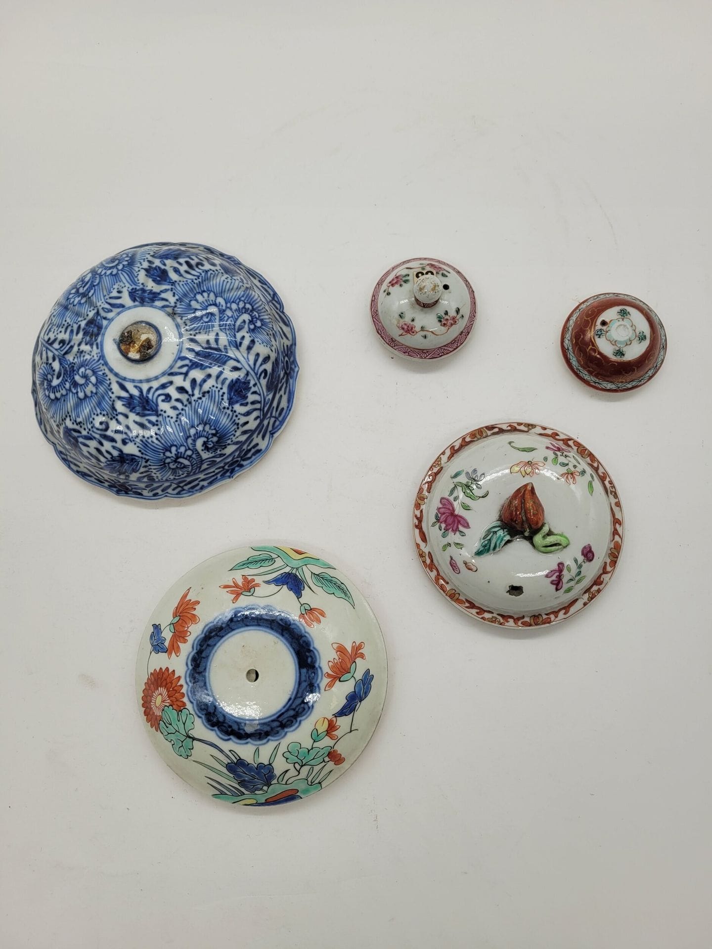 17 couvercles en porcelaine et 1 en émaux cloisonnés, Chine et Japon, XVIIe - XVIIIe et XIXe siècles
- Huit couvercles de pièces de forme en porcelaine de la Compagnie des Indes émaillés famille rose, Imari et bleu sous couverte ; - un couvercle émaillé rouge et vert d'époque Transition; - quatre couvercles de vases bleu et blanc d'époque Kangxi, trois couvercles Imari, Japon, surmontés d'un chien de Fô ; - un couvercle de la manufacture de Samson ; - un couvercle de brûle-parfum en émaux cloisonnés avec un bouton de préhension ajouré orné de chauves-souris dans les nuages et d'un signe shou, époque Jiaqing.
Longueur : de 4,6 à ?? cm
Restaurations et fêles.