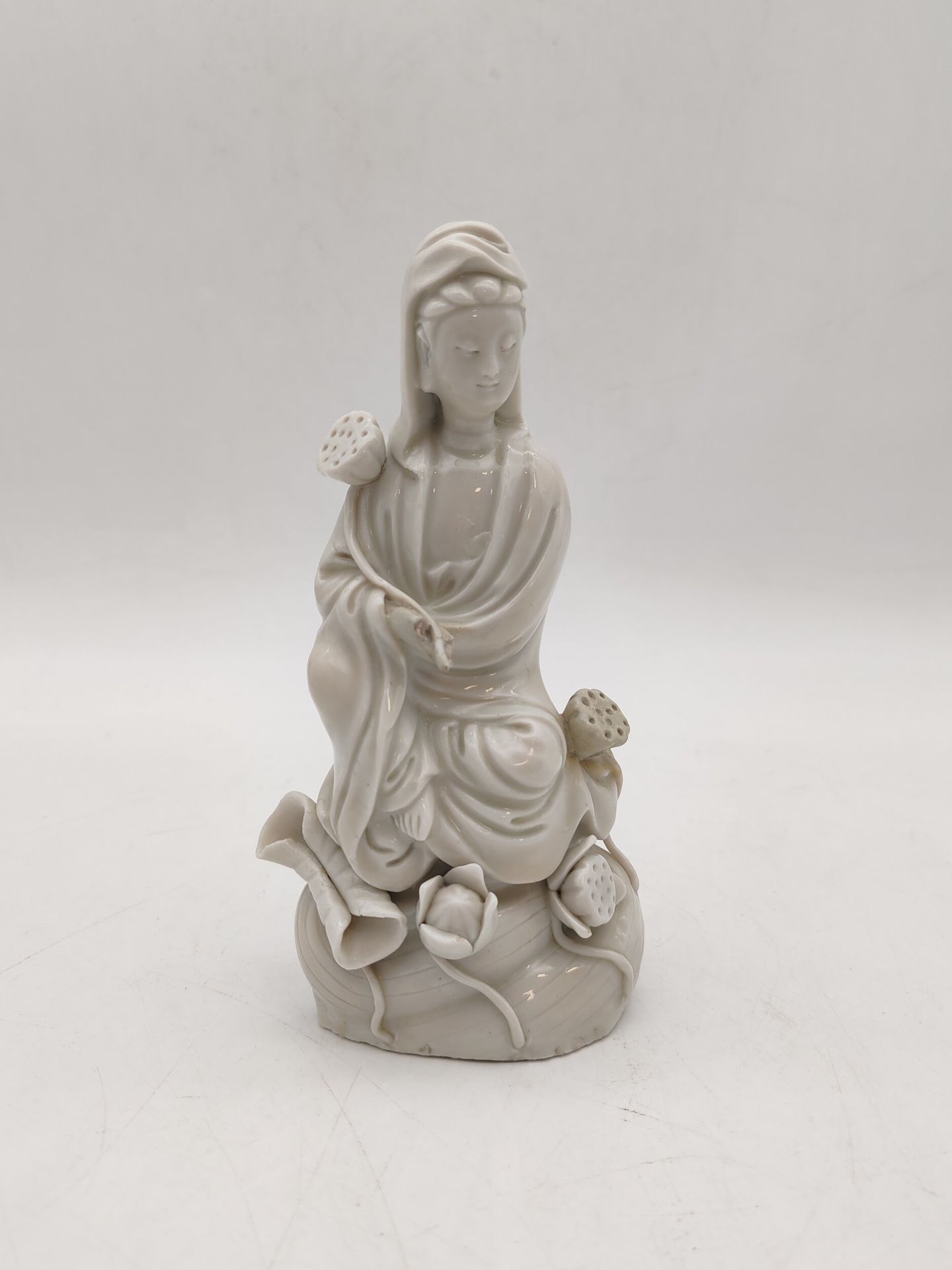 Guanyin en porcelaine blanc de Chine, Chine, Dehua, époque Kangxi, XVIIe siècle
La divinité est représentée assise sur les flots parmi des feuilles, fleurs et boutons de lotus. Le visage est serein, les yeux baissés et les cheveux rassemblés en chignon sous un vêtement tombant en plis autour du corps et ouvert sur la poitrine. Elle tient un bouton de lotus dans la main droite.
Hauteur : 18 cm
Manque une main. Restaurations.