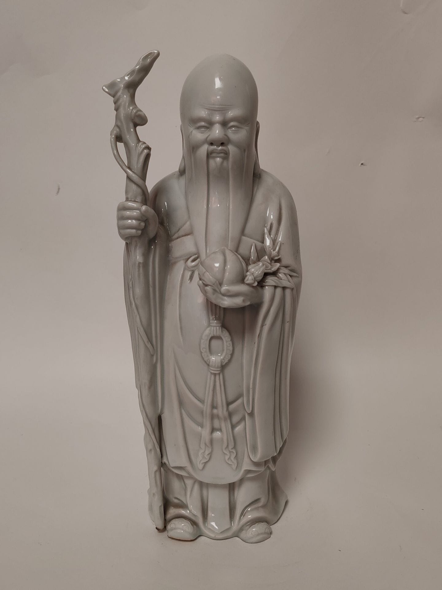 Shou Lao en porcelaine à couverte blance, Chine, XXe siècle
Se tenant debout, tenant son baton dans la main droite et la pêche de longévité dans la main gauche. 
Hauteur : 32 cm