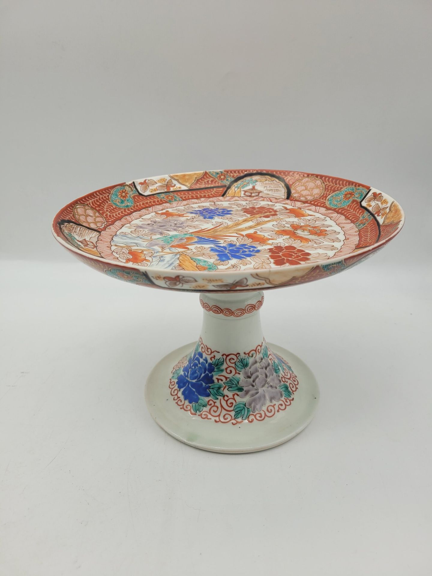Porcelain display stand with high foot, Japan, Meiji period
The tray decorated with a phoenix among chrysanthemums. Inscriptions under the base.
Height: 15.5 cm
Fels and chips.