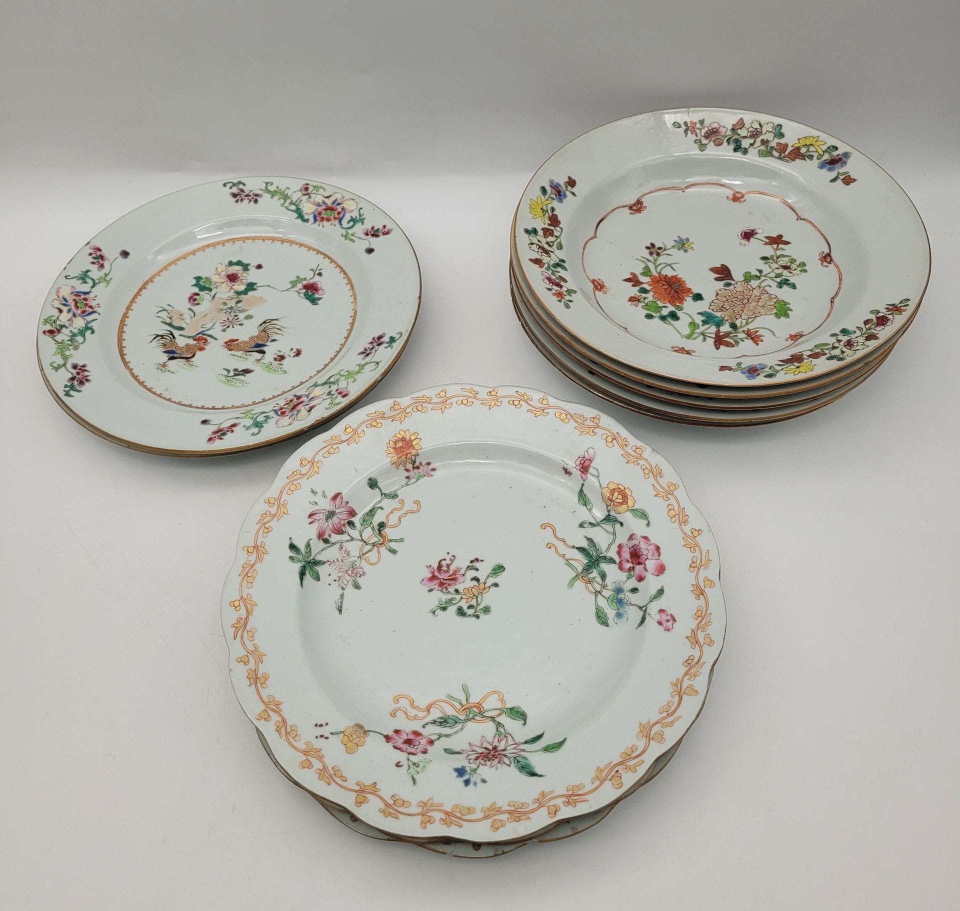 10 porcelain plates, China, Compagnie des Indes, 18th century
Including 
- 5 with lotus and chrysanthemum design.
- 3 with floral motif and gilded frieze on rim.
- 2 with central motif of roosters in flowering rocks. 
Diameter: 22.3 to 23 cm
Fels, chips, some plates broken and glued.