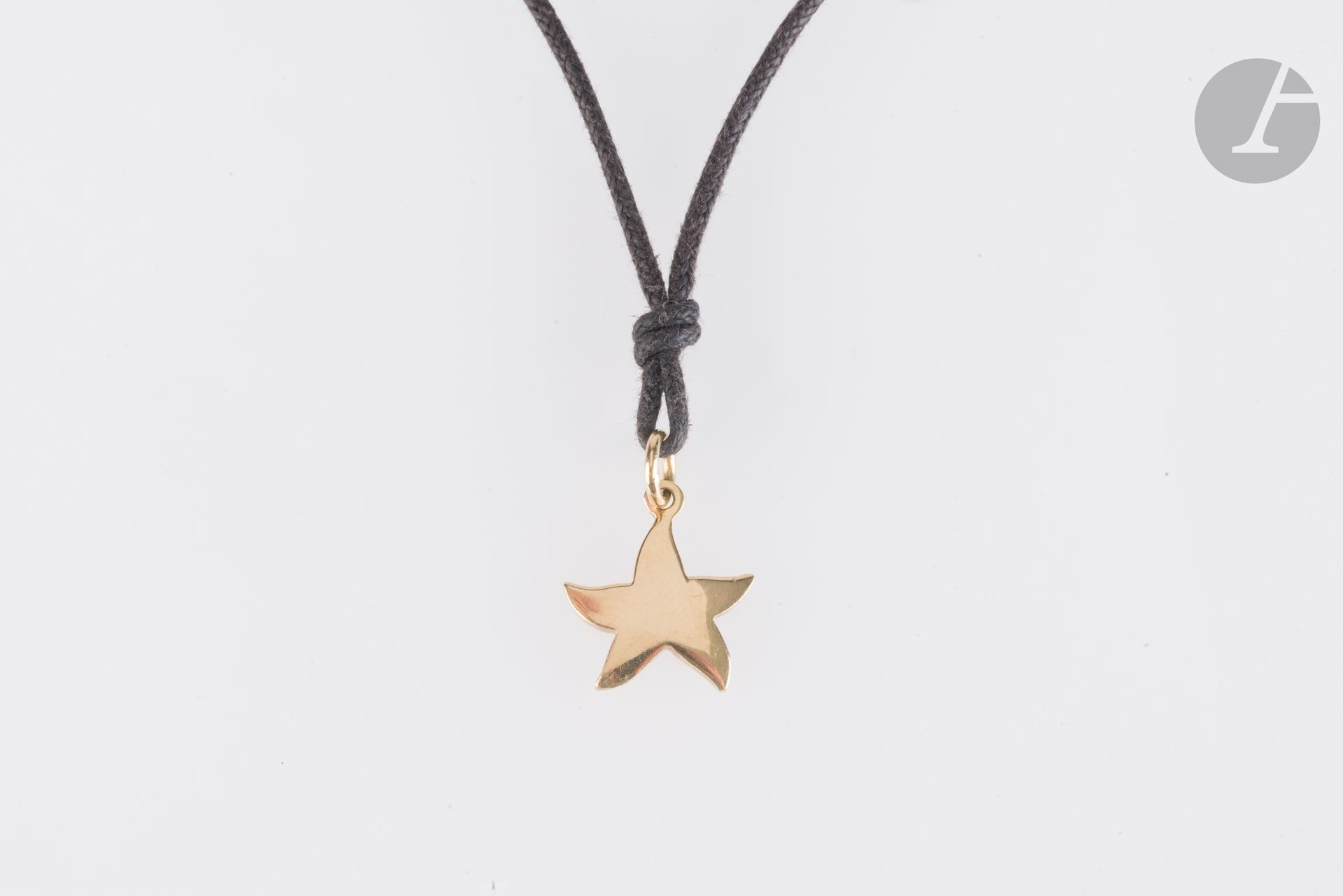 DODO
Pendentif en forme d'étoile en or 18K (750) coulissant sur une cordelette en coton. Signé. Hauteur : 1,3 cm environ. Poids brut : 2,6 g (à renouer)